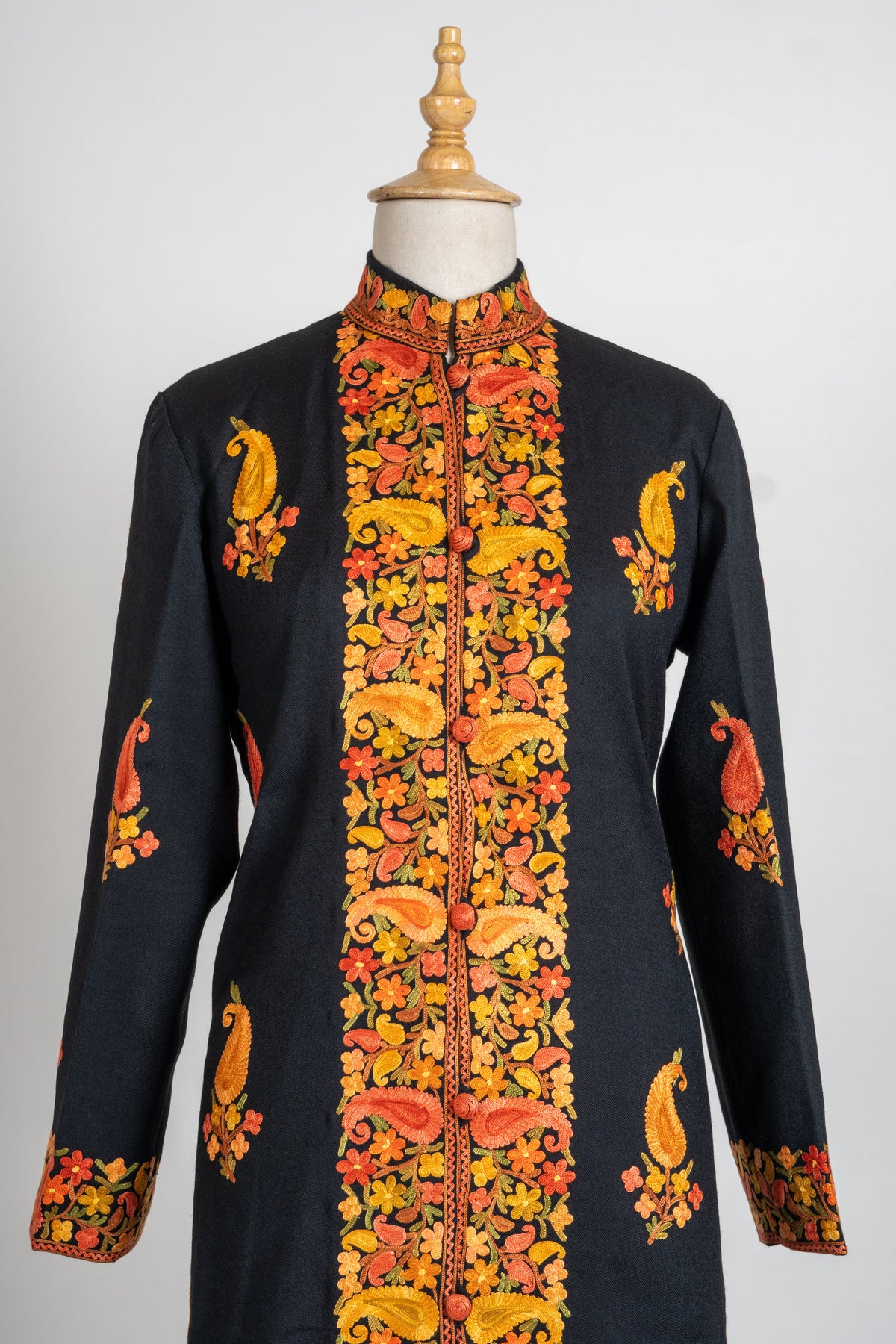 Front view of the black jacket with orange and gold Aari floral borders and spaced paisley sprigs