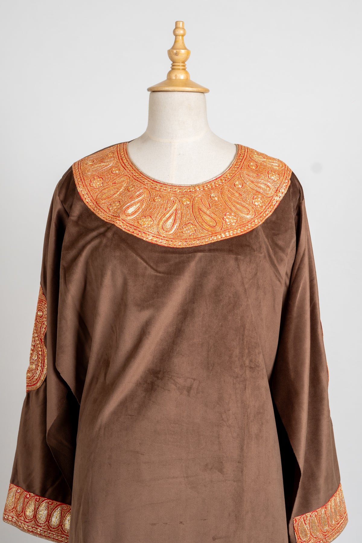 Upper front of the brown velvet pheran with a broad gold-toned embroidered neckline and matching cuff borders.
