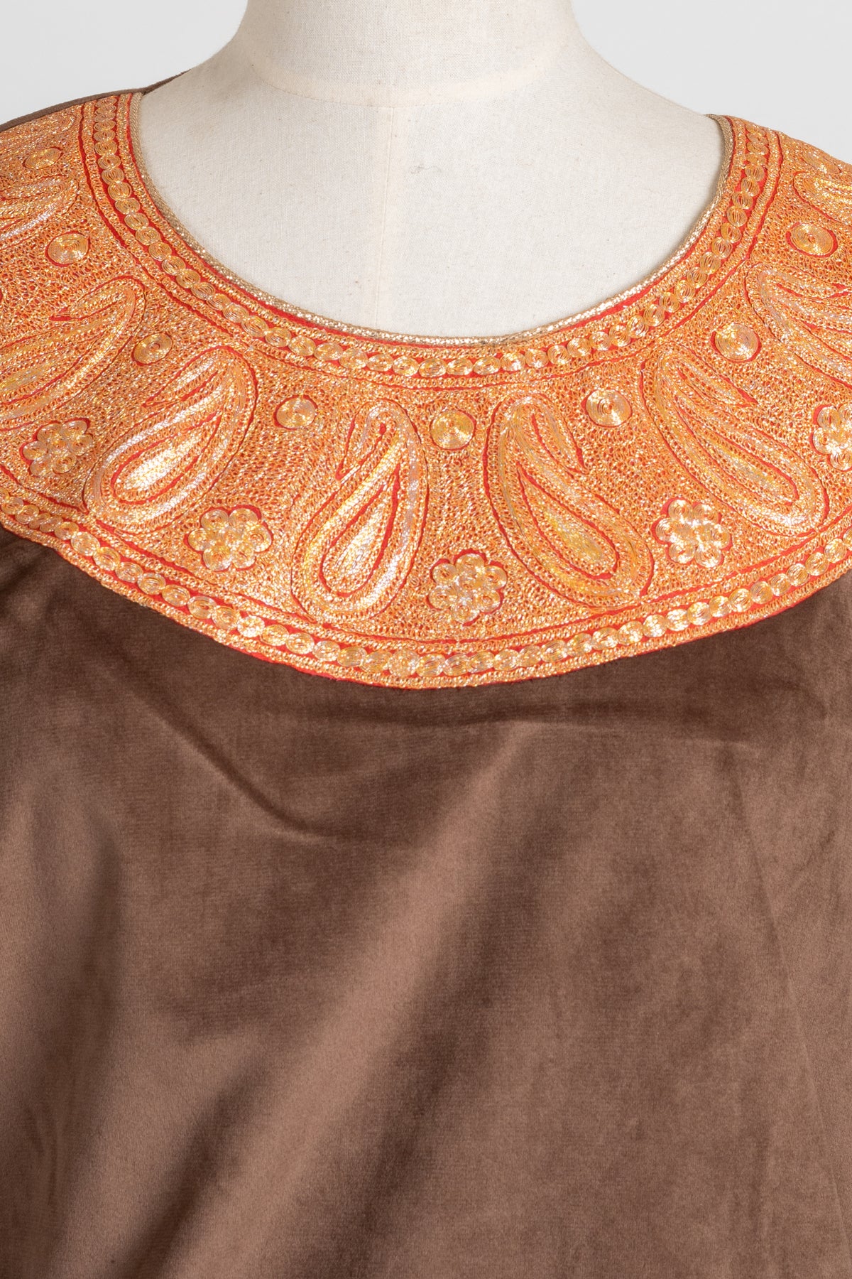 Close-up of gold-toned Tilla paisleys and small floral details around the brown velvet pheran’s round neckline.