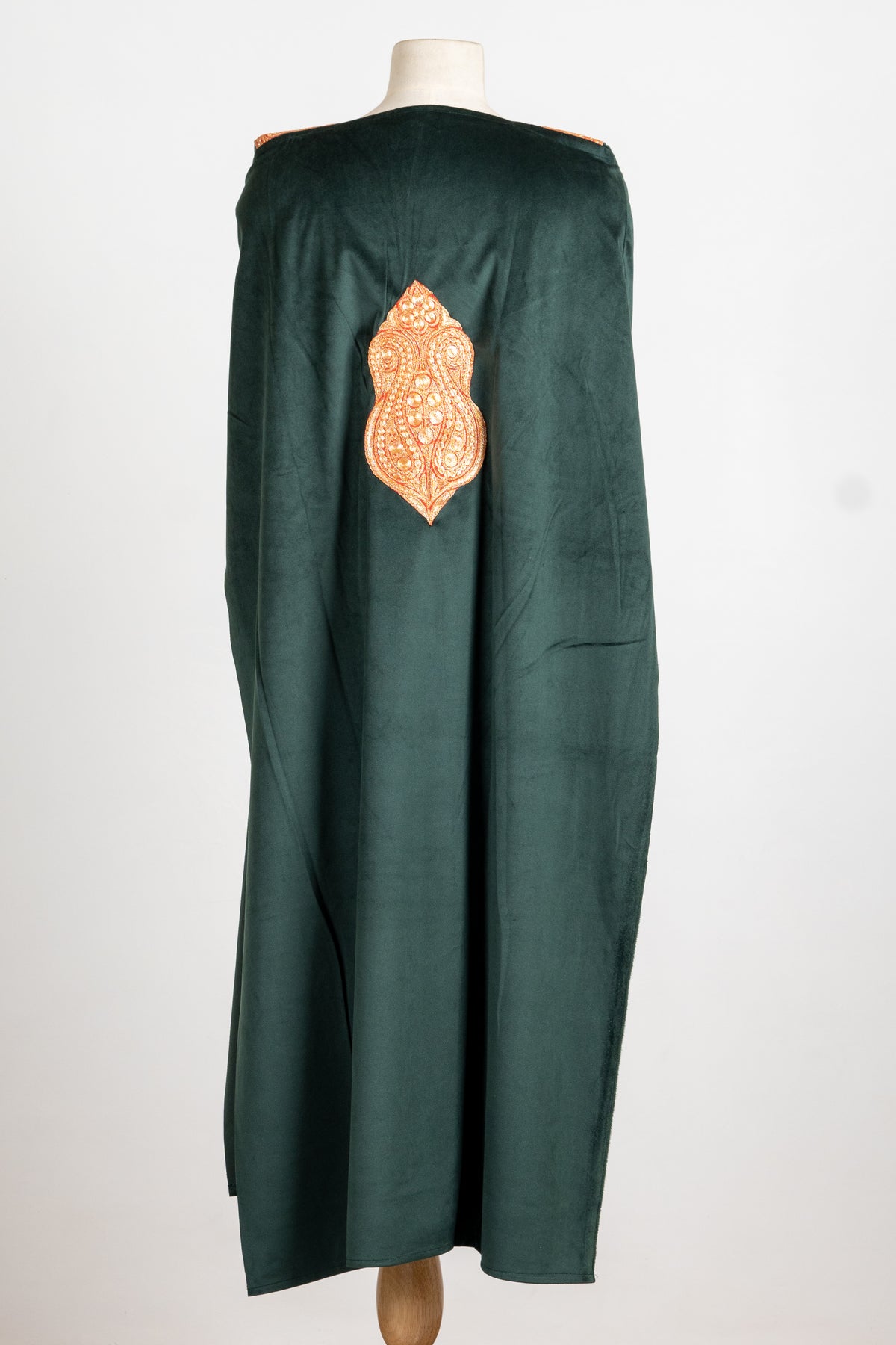 Back of a forest green velvet suit top with a single copper-gold Tilla paisley medallion below the shoulders