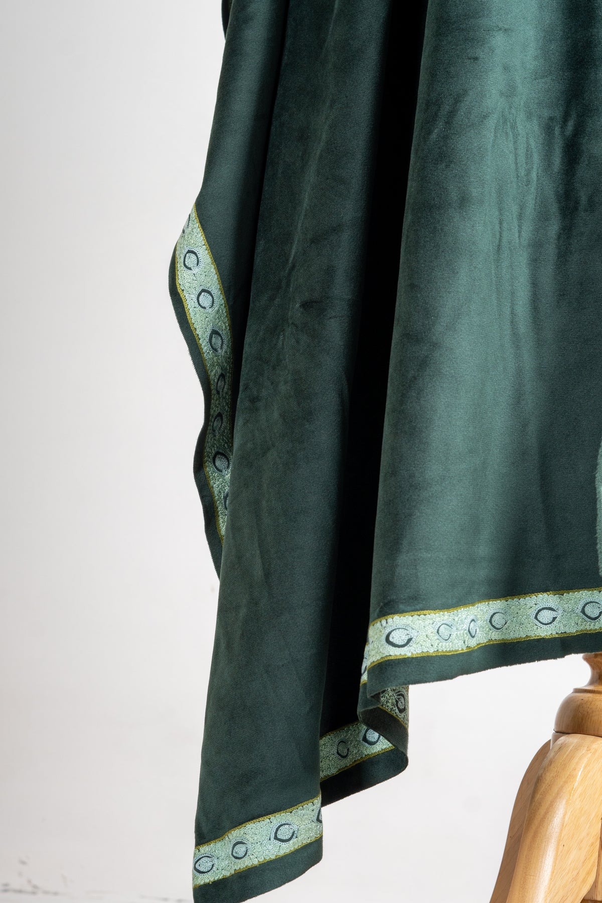 Hanging green velvet stole with a narrow pale embroidered border of linked curved motifs