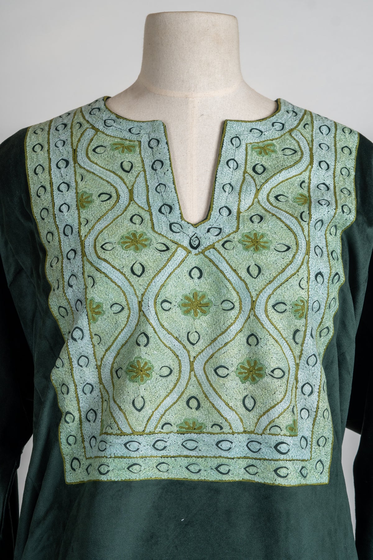 Close-up of the suit’s pale green Aari neckline panel with wavy vines, small flowers and a notched opening