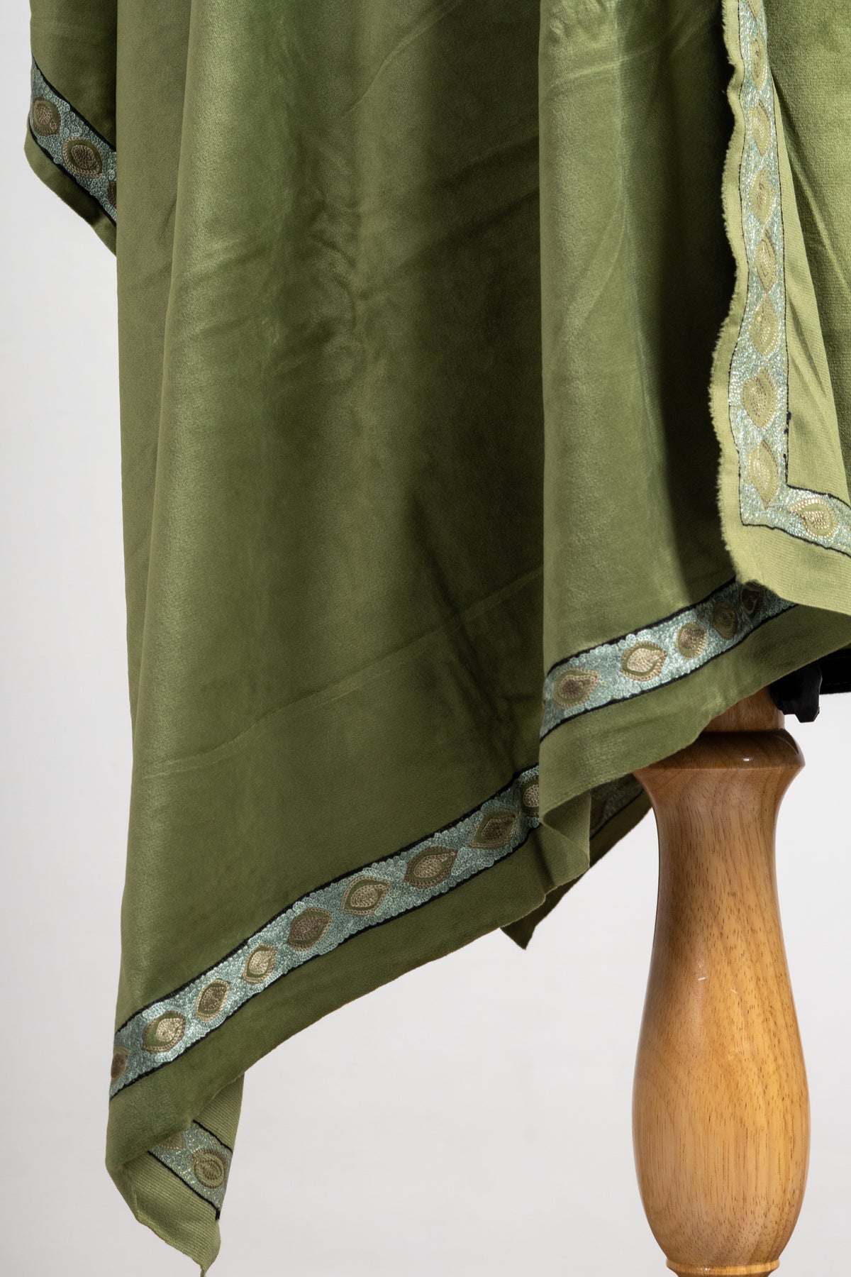 Hanging corner of the olive velvet stole with a pale blue border of gold-coloured oval motifs.