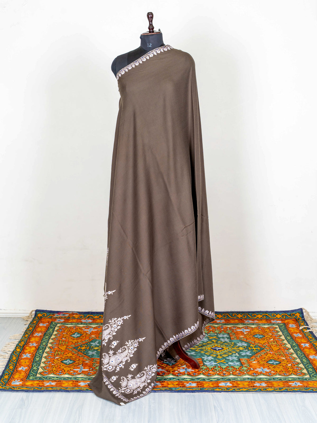 Full-length view of the mocha-brown Pashmina shawl on a mannequin, showing its long drape and embroidered end