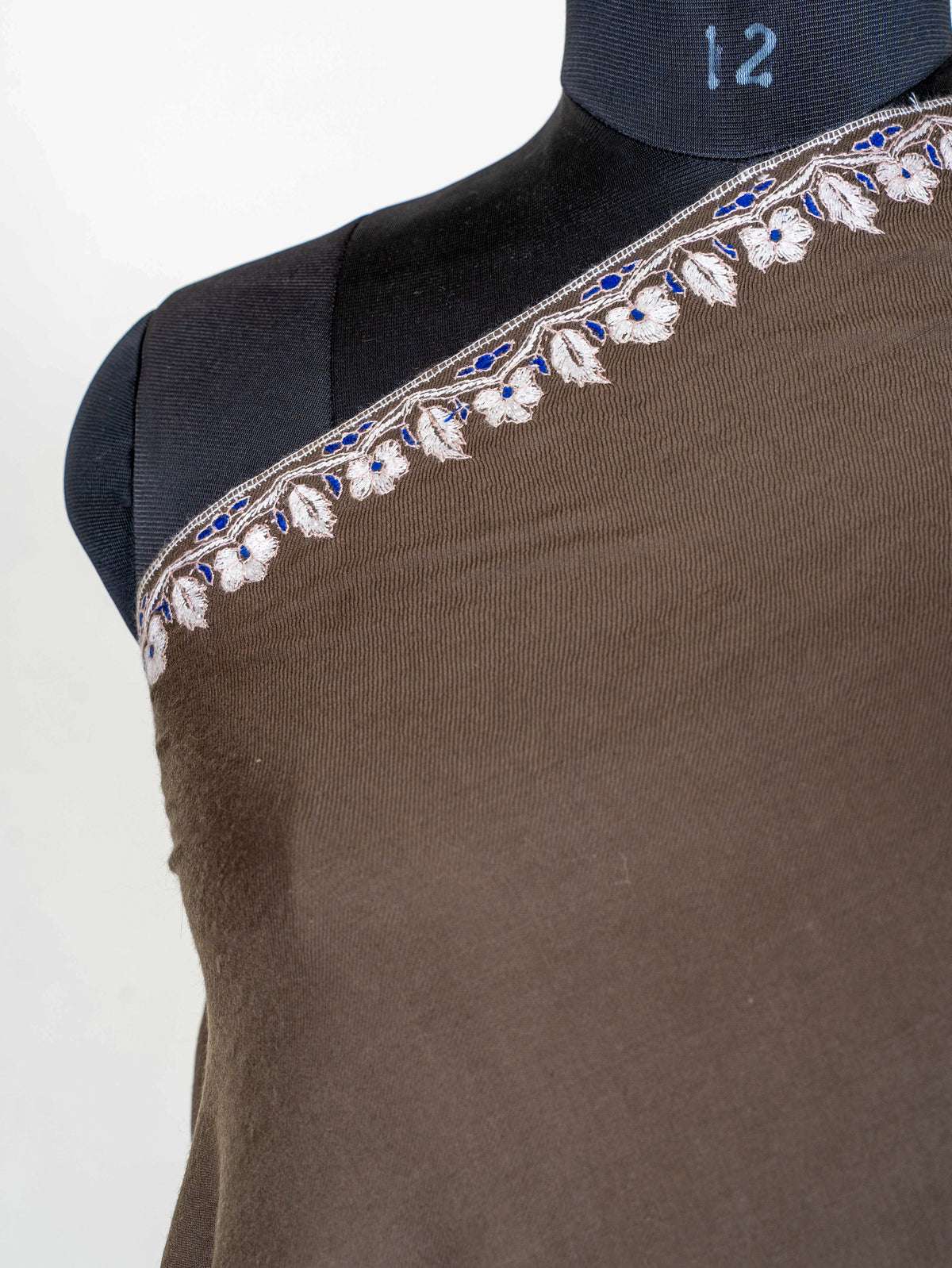 Close-up of the mocha-brown shawl's shoulder border, with small ivory flowers and blue accents