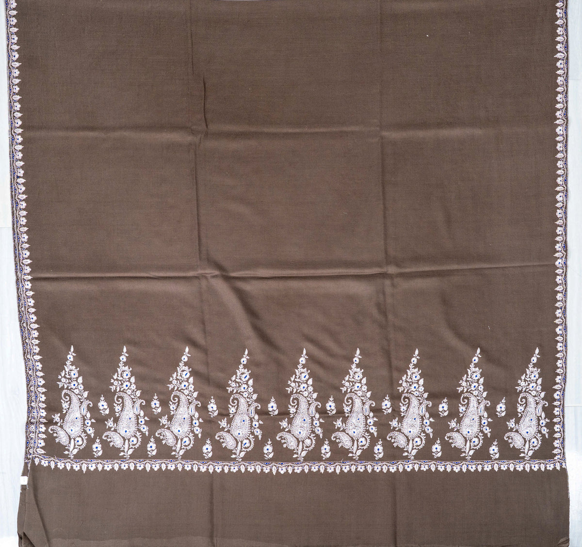 Mocha-brown Pashmina shawl laid flat, showing a plain centre framed by narrow side borders and ivory end motifs