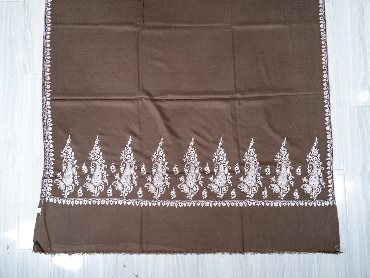 Lower end of the mocha-brown Pashmina shawl laid flat, with a row of ivory paisley and floral Sozni motifs
