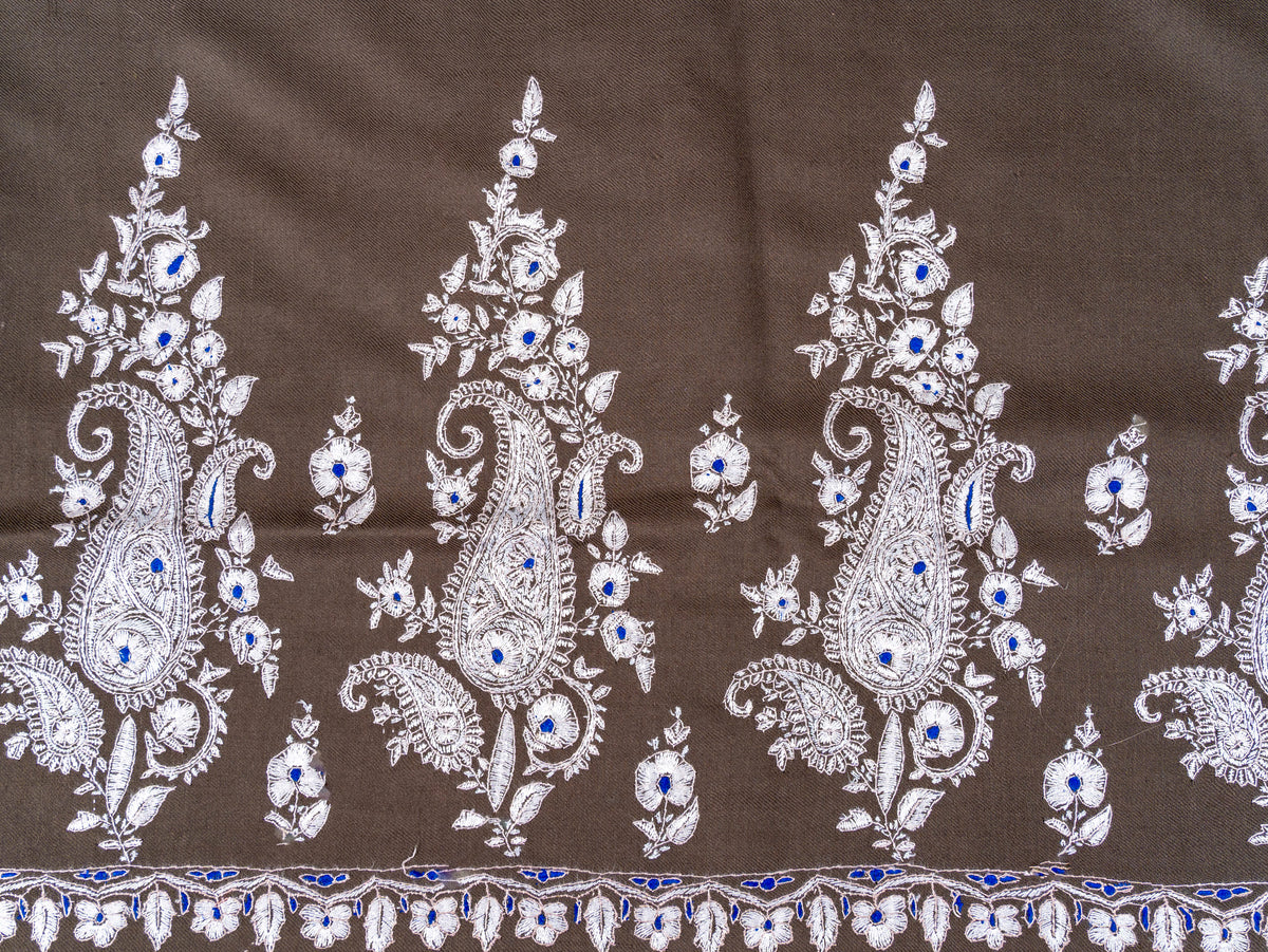 Detail of three ivory paisley and floral sprays with blue accents on the mocha-brown Pashmina shawl