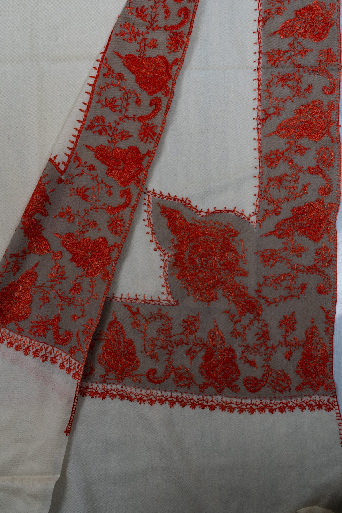 Folded ivory shawl corner showing both sides of red Sozni flowers and curling vines along a broad border