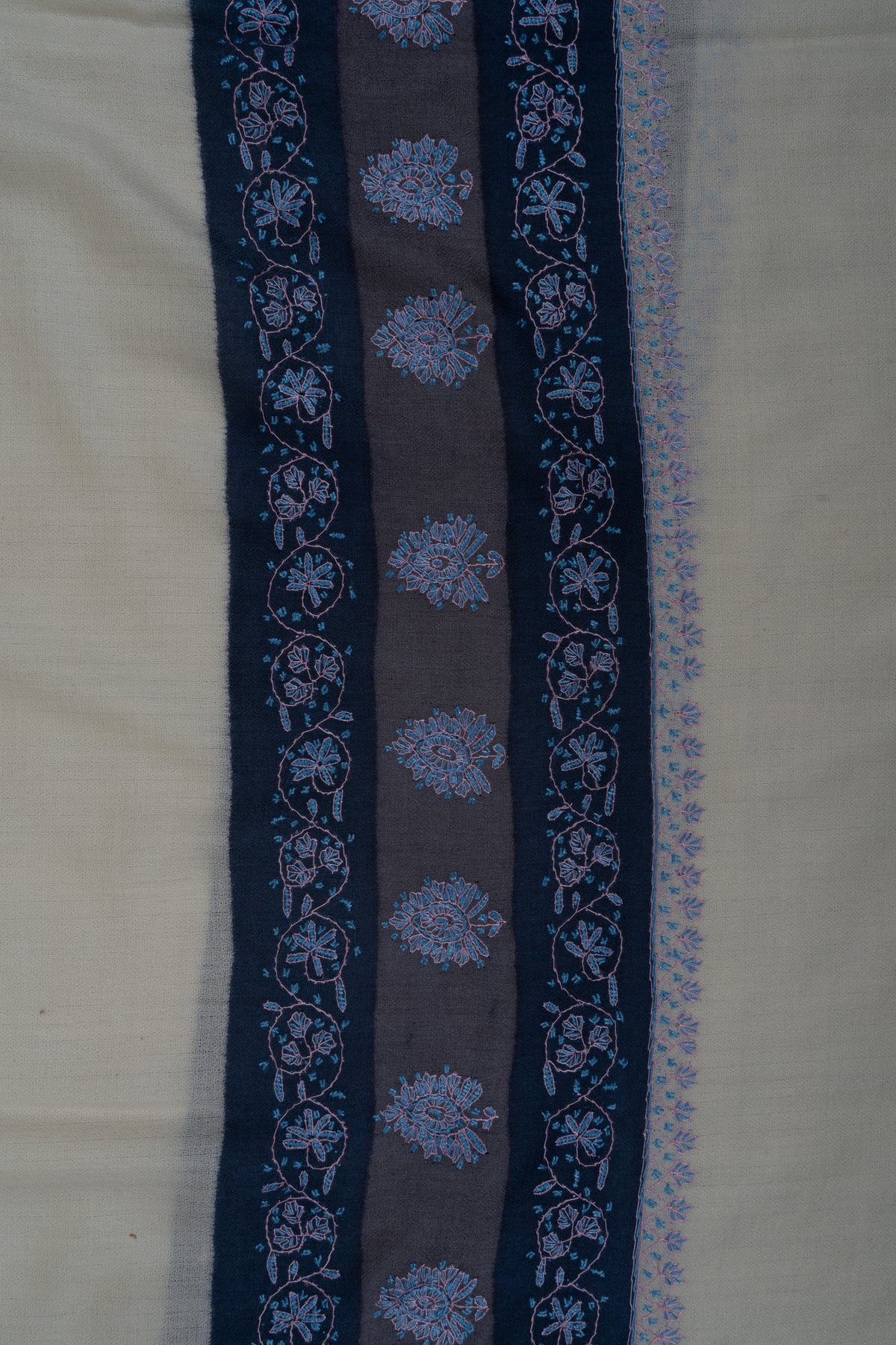Close-up of the ivory shawl's navy and grey-blue border bands with pale blue floral medallions