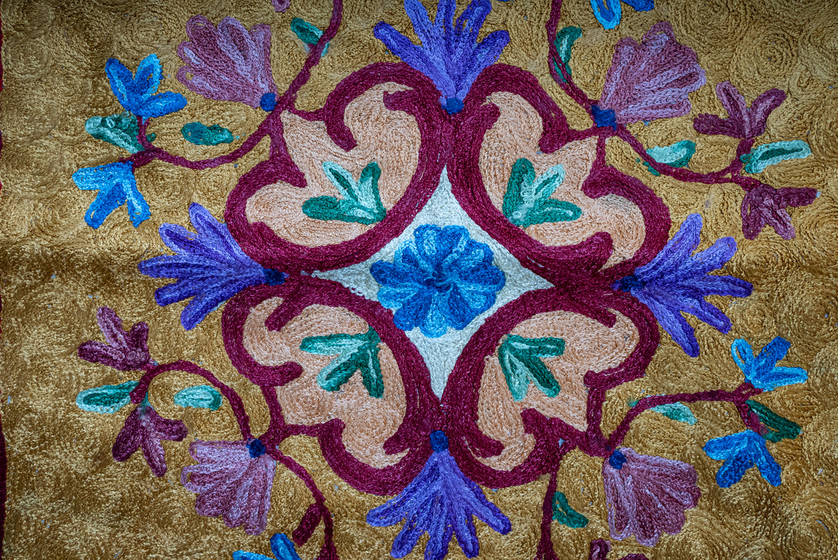 Close-up of the prayer mat's symmetrical multicoloured floral medallion on a golden ground