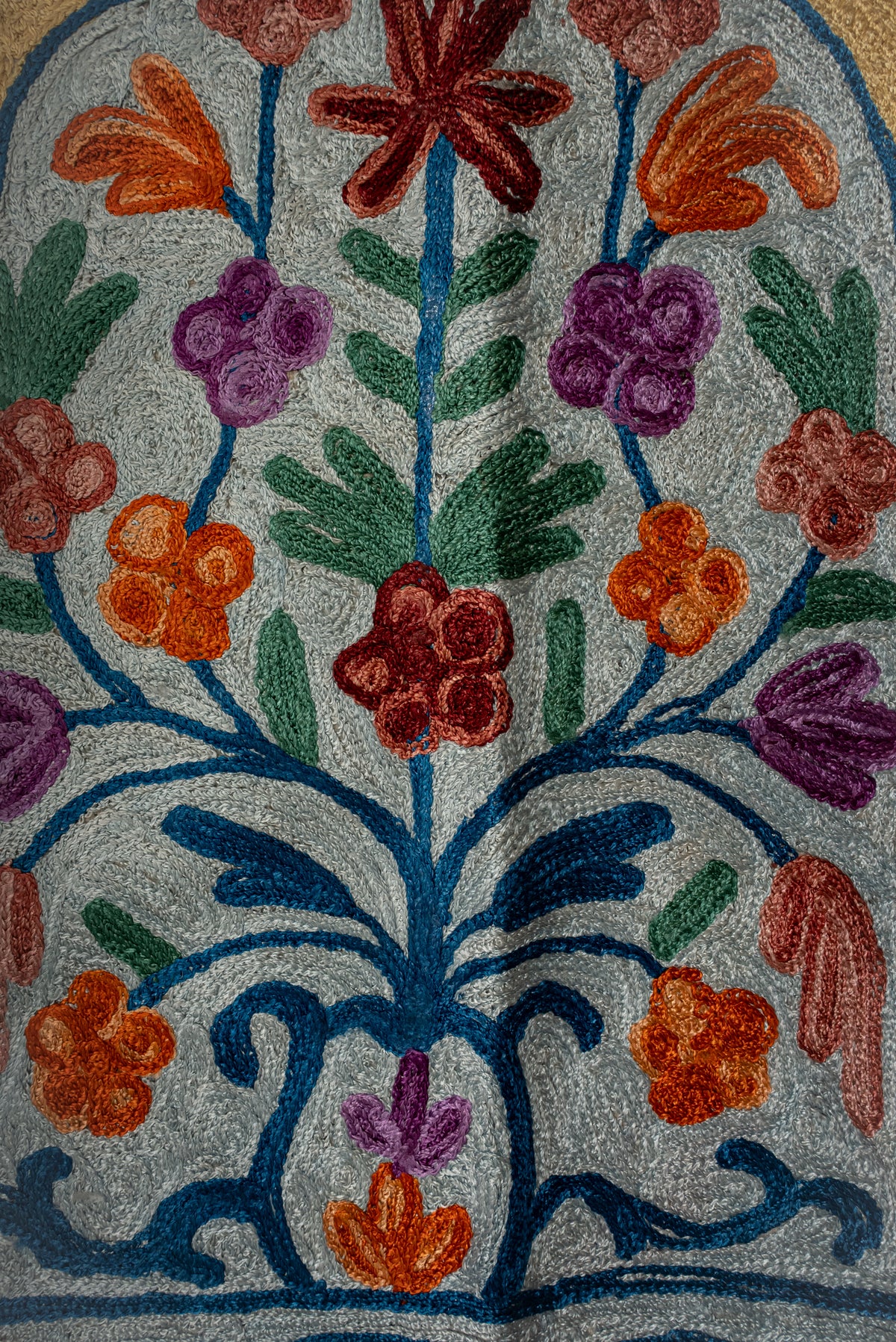 Close-up of blue scrolling stems with orange, pink and purple flowers and green leaves on the prayer mat