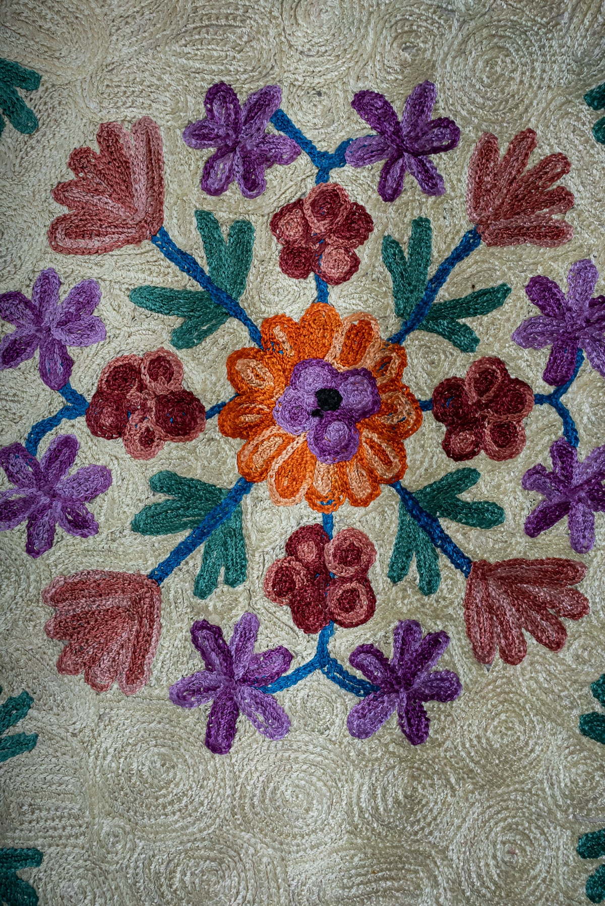 Close-up of the prayer mat's orange center flower surrounded by purple, pink and burgundy blossoms