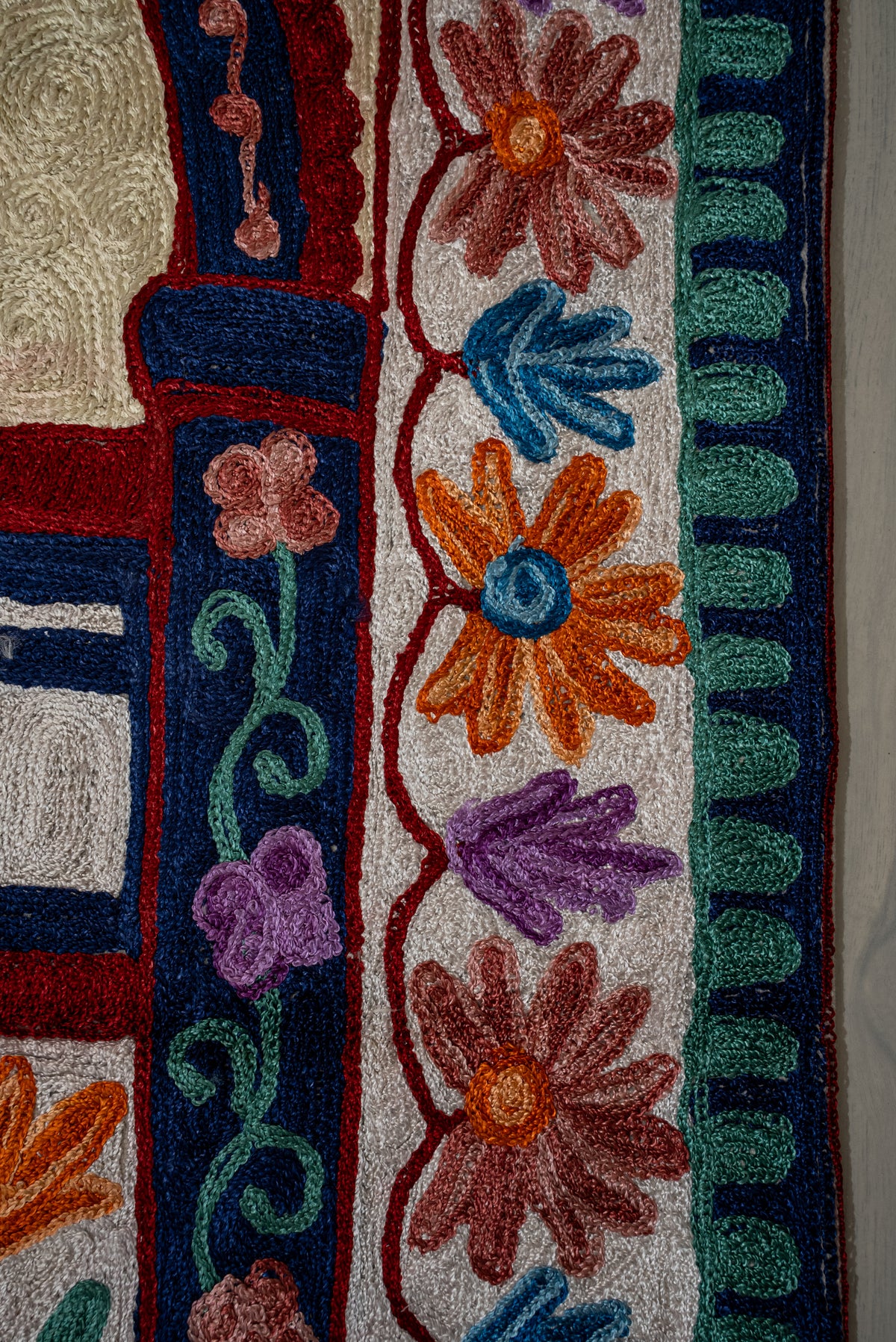 Detailed view of embroidered flower borders, a blue floral column and teal edging on the prayer mat