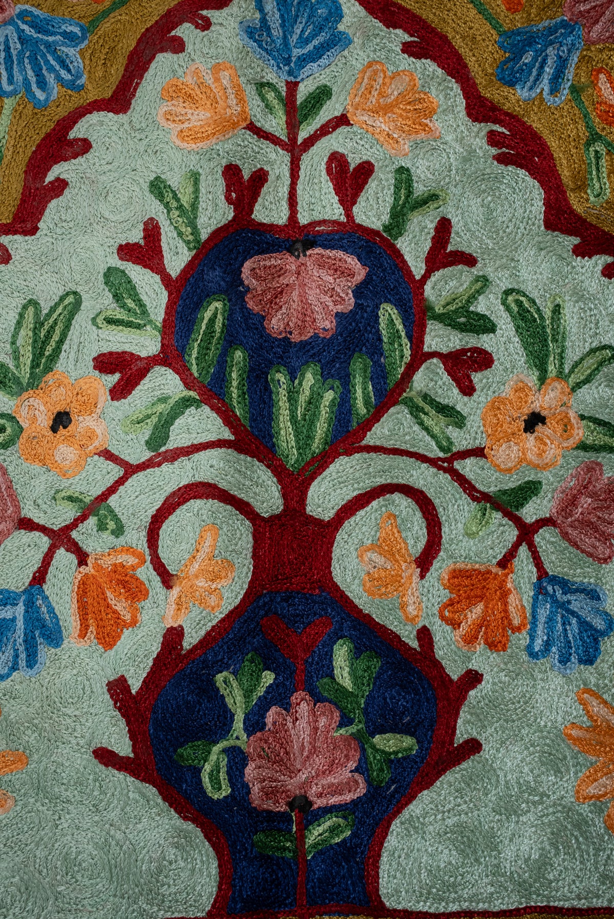 Close-up of navy vase motifs and pink, orange and blue flowers on the prayer mat's pale green ground