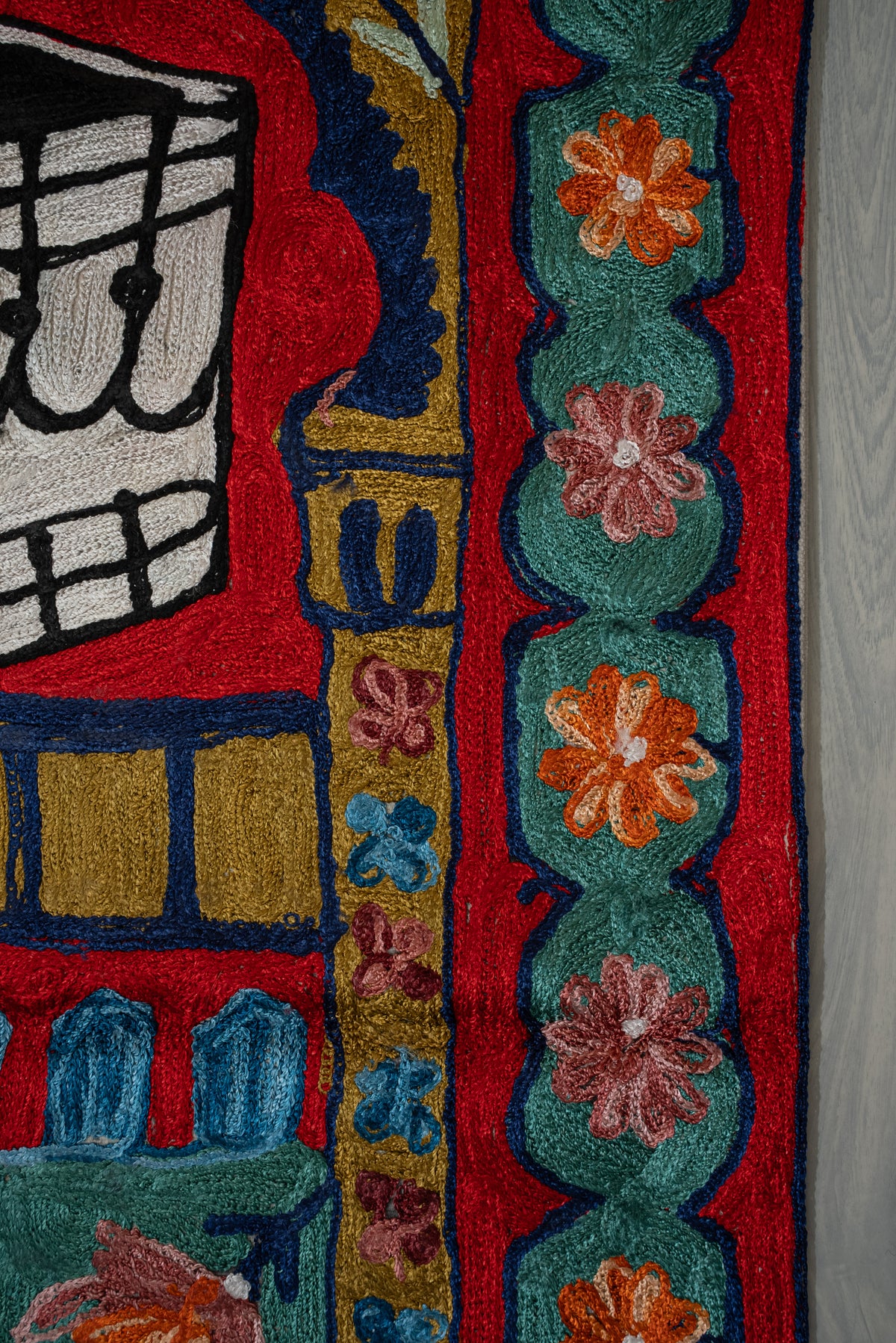 Close-up of the prayer mat's teal flower border and gold column beside the black-and-white Kaaba motif