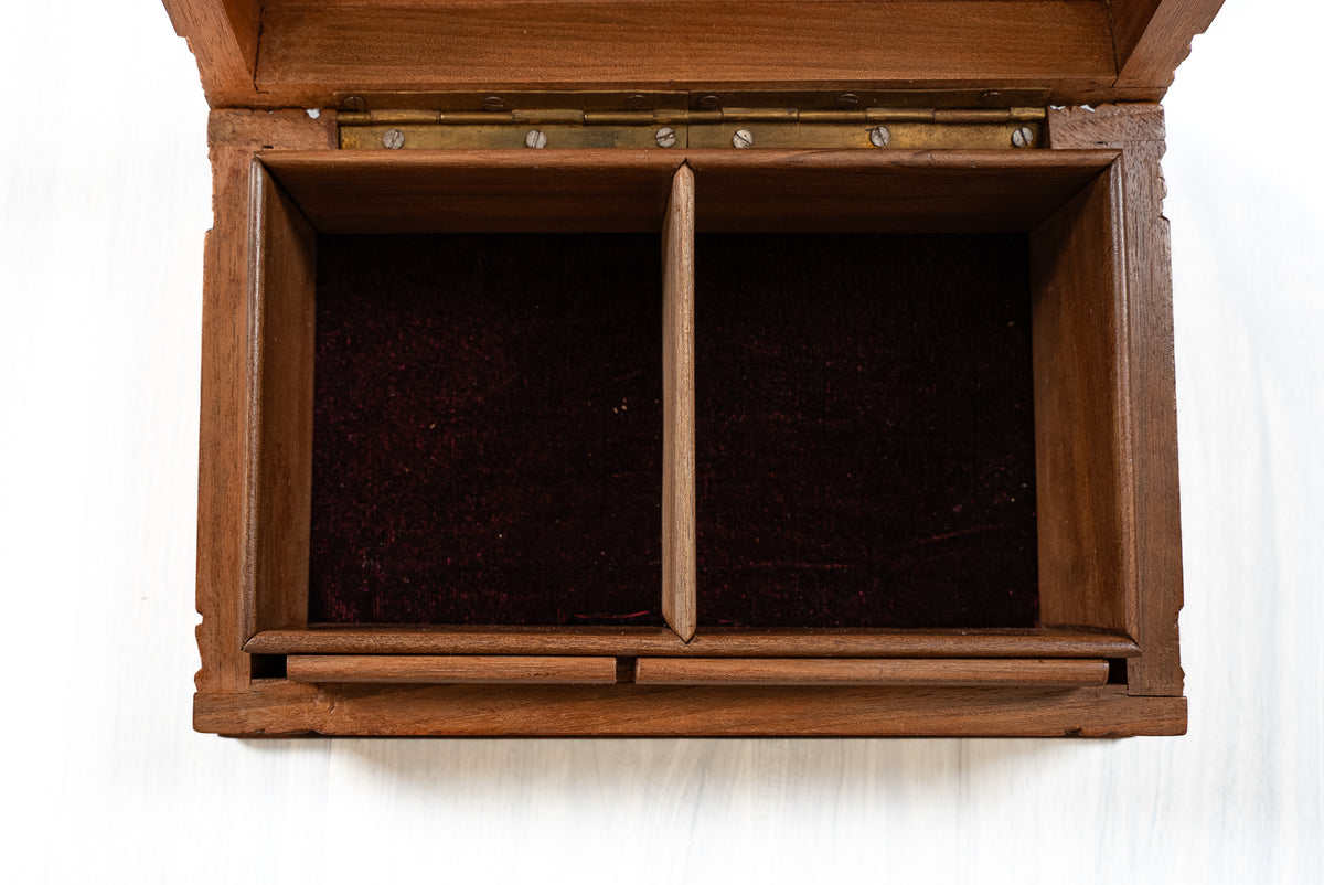 Overhead close-up of an open walnut wood box showing the central divider, two dark-lined compartments and long lid hinge