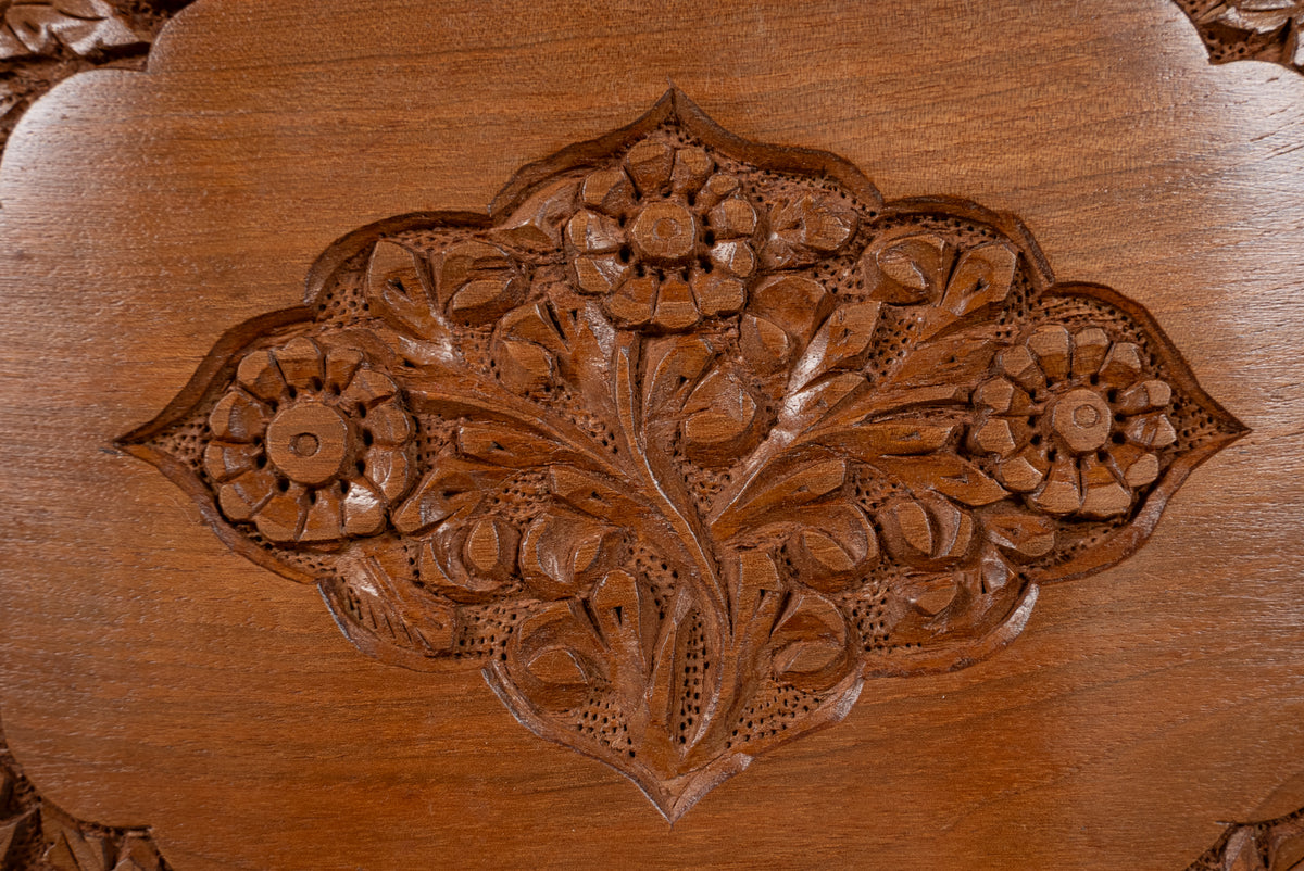 Close-up of the three-flower medallion and curling leaves carved into a walnut wood box lid