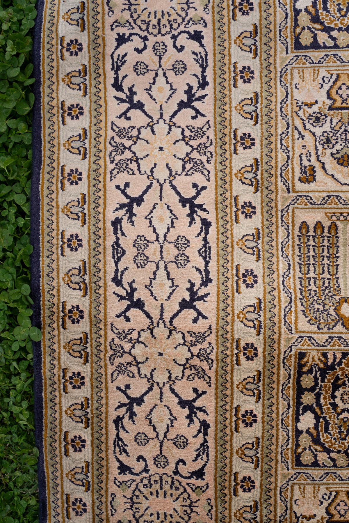 Detail of the ivory silk carpet's navy floral vine border and narrow patterned bands