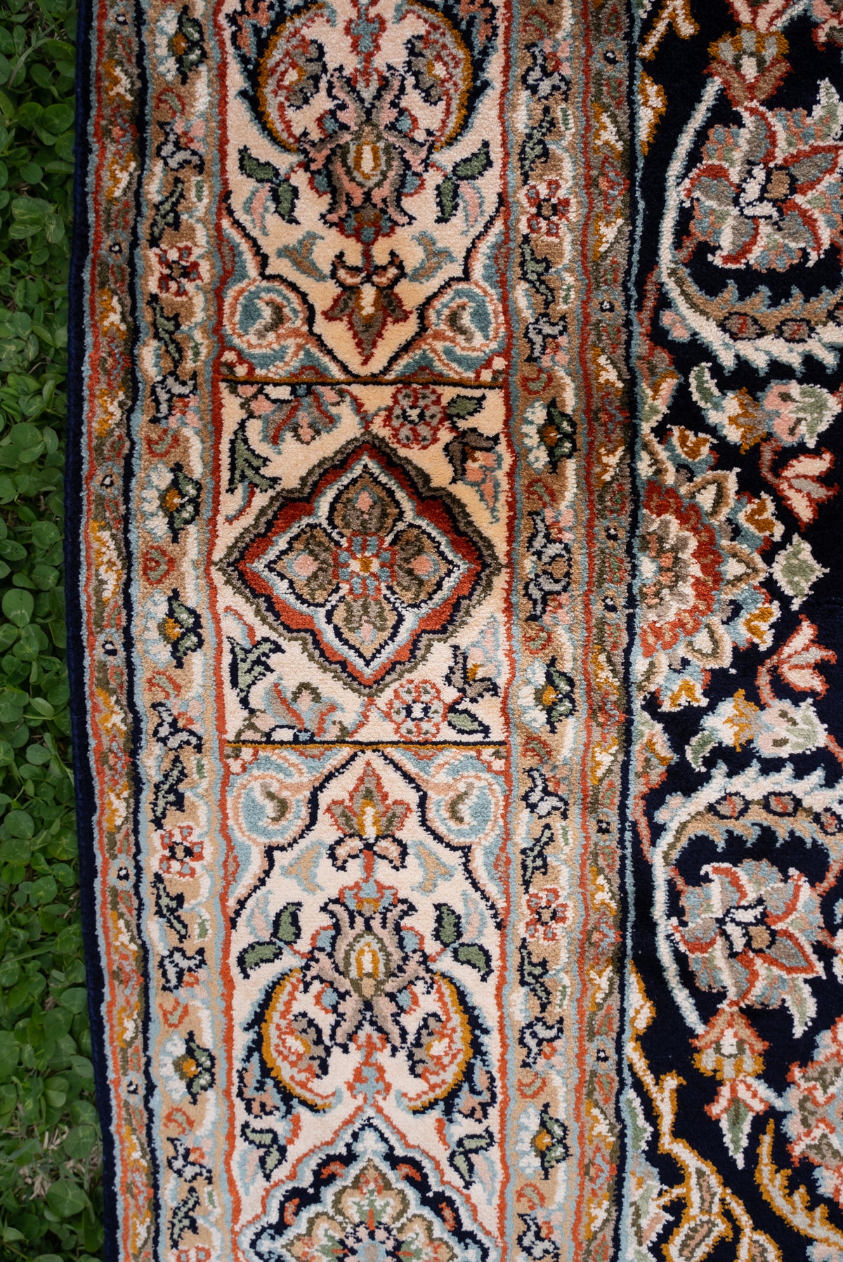 Side border of a dark mulberry silk carpet with cream floral panels, rust outlines and narrow patterned bands