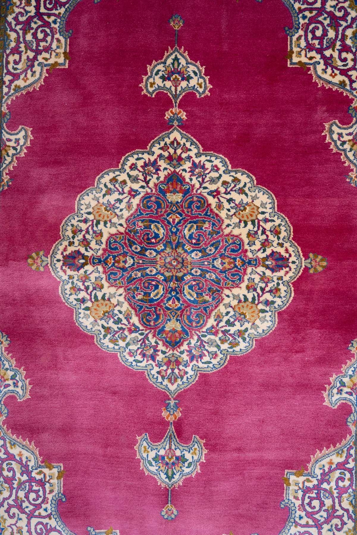 Rose-pink silk carpet field with a scalloped cream and blue medallion and pendant motifs