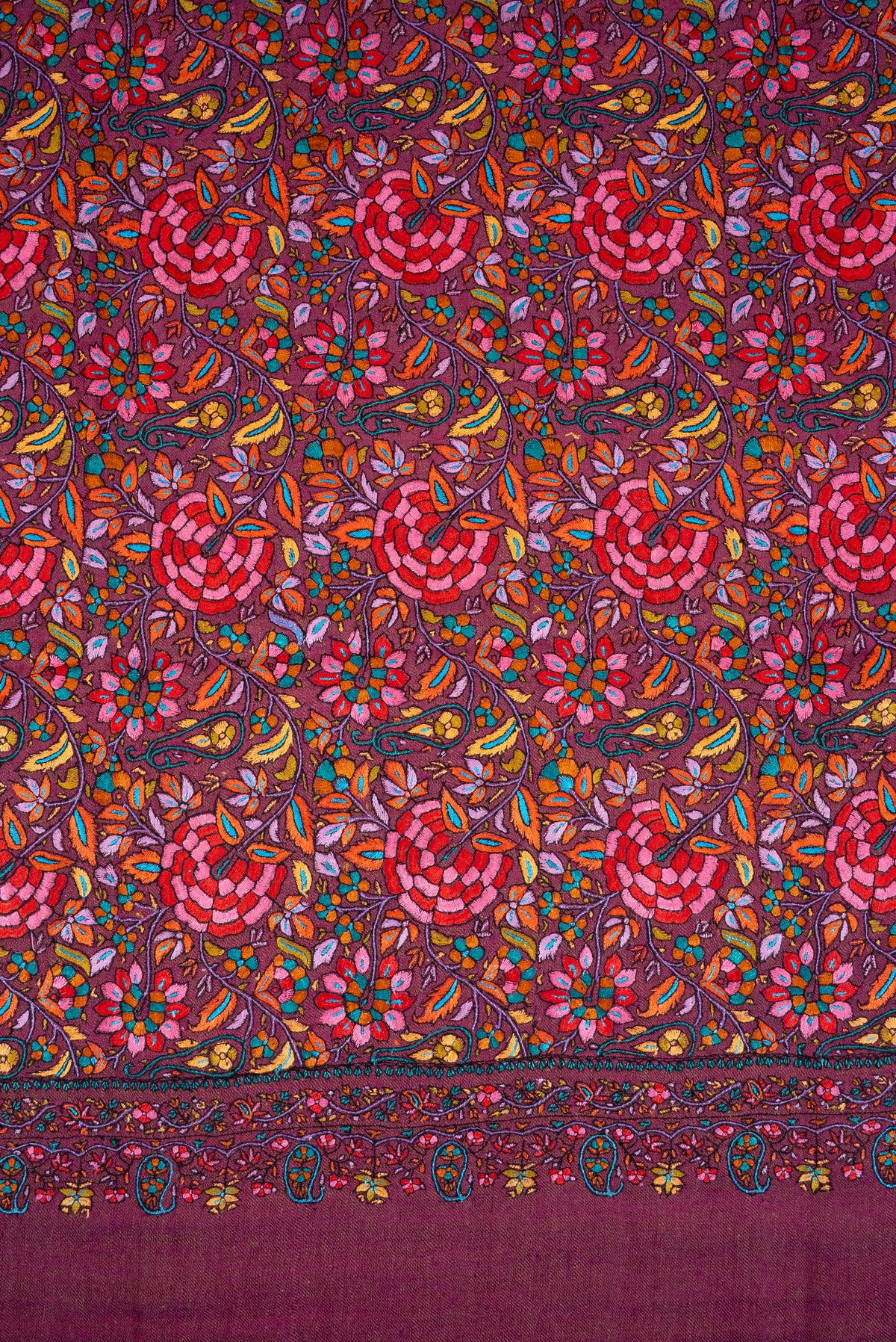 Flat detail of pink and red flowers, orange and yellow leaves, and turquoise accents densely embroidered on plum Pashmina