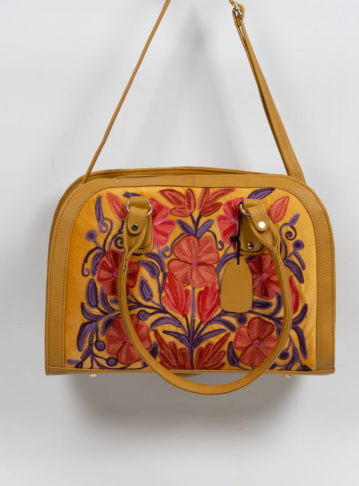 Mustard floral bag hanging from its long shoulder strap, with the short handles folded down across the embroidered front.