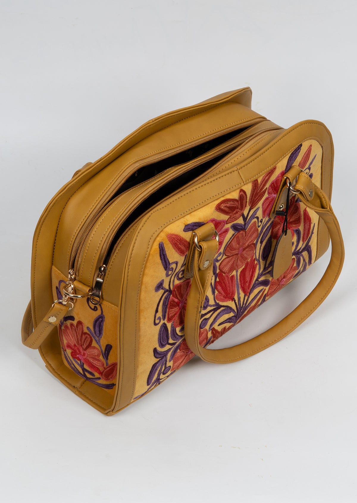 Top angled view of the mustard floral bag with its zipper partly open and short handles resting against the front.