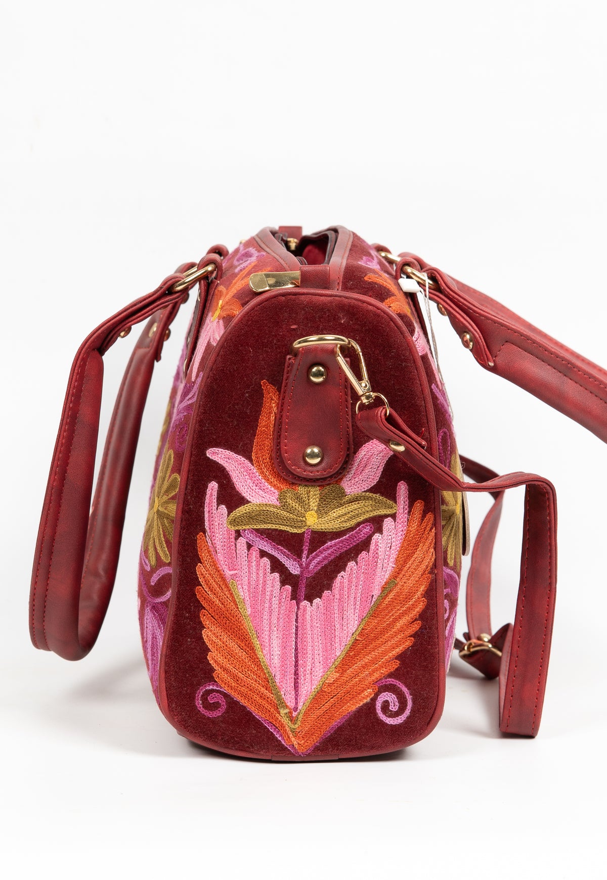 Side view of the maroon handbag, with a large pink-and-orange embroidered leaf motif and a clipped shoulder strap
