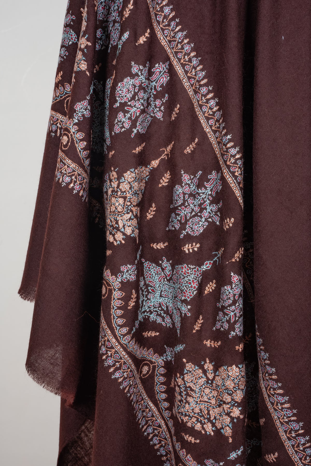 Draped chocolate-brown Pashmina shawl end, with blue, pink and beige embroidered floral bouquets framed by fine borders.