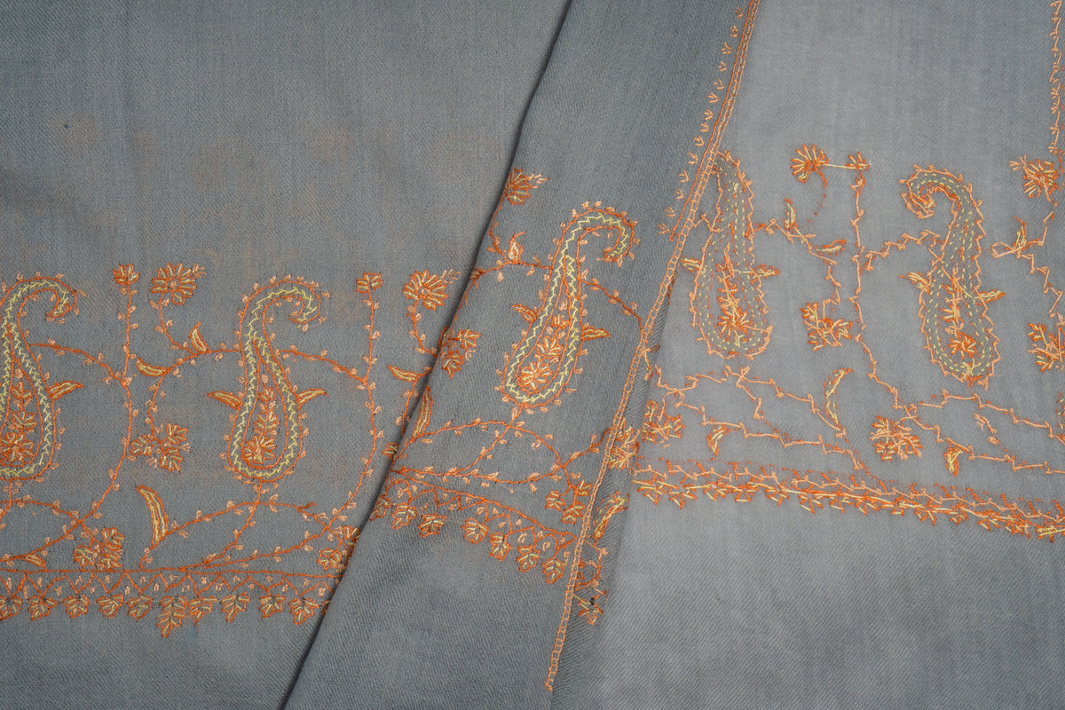 Close-up of overlapping grey stole ends with fine orange paisley motifs and small floral border details.