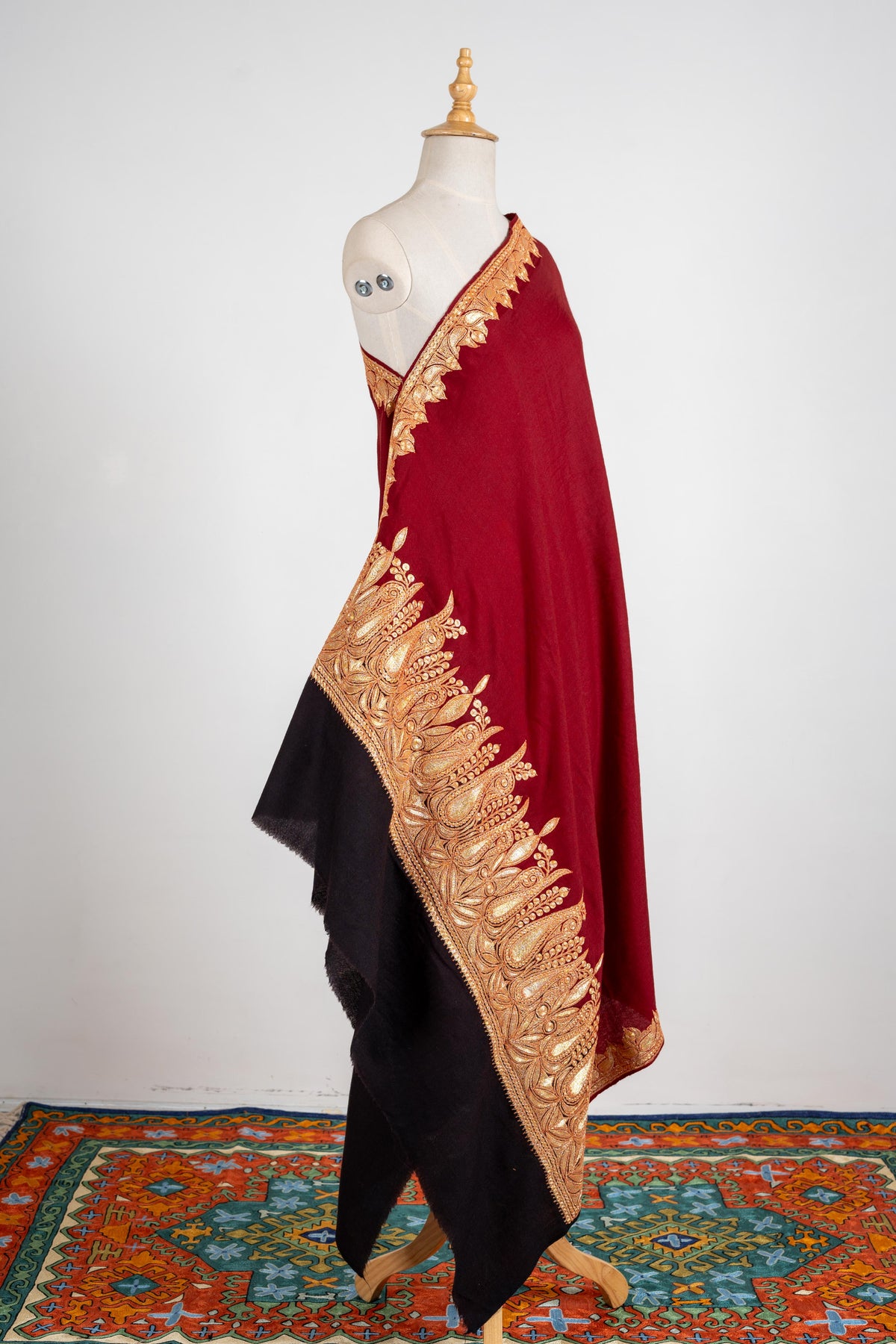 Full draped view of the crimson shawl with gold-coloured embroidered borders and a contrasting black end panel.