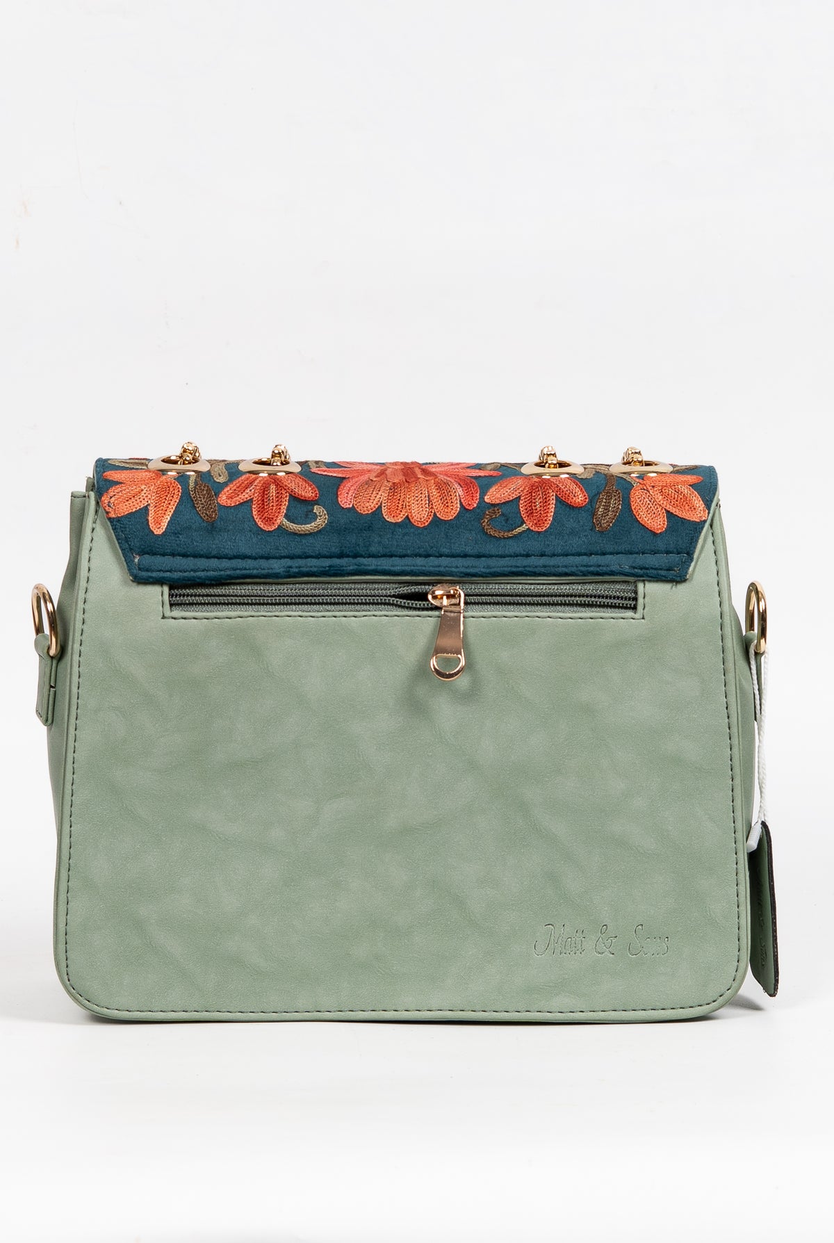 Back of the pale green chain bag with a horizontal zip pocket and a teal floral embroidered flap edge