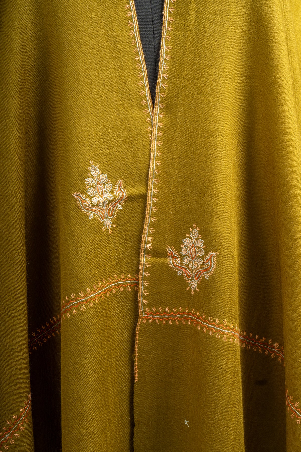 Close-up of pale floral Sozni motifs on the olive-green stole beside fine embroidered edging along its overlapping ends.