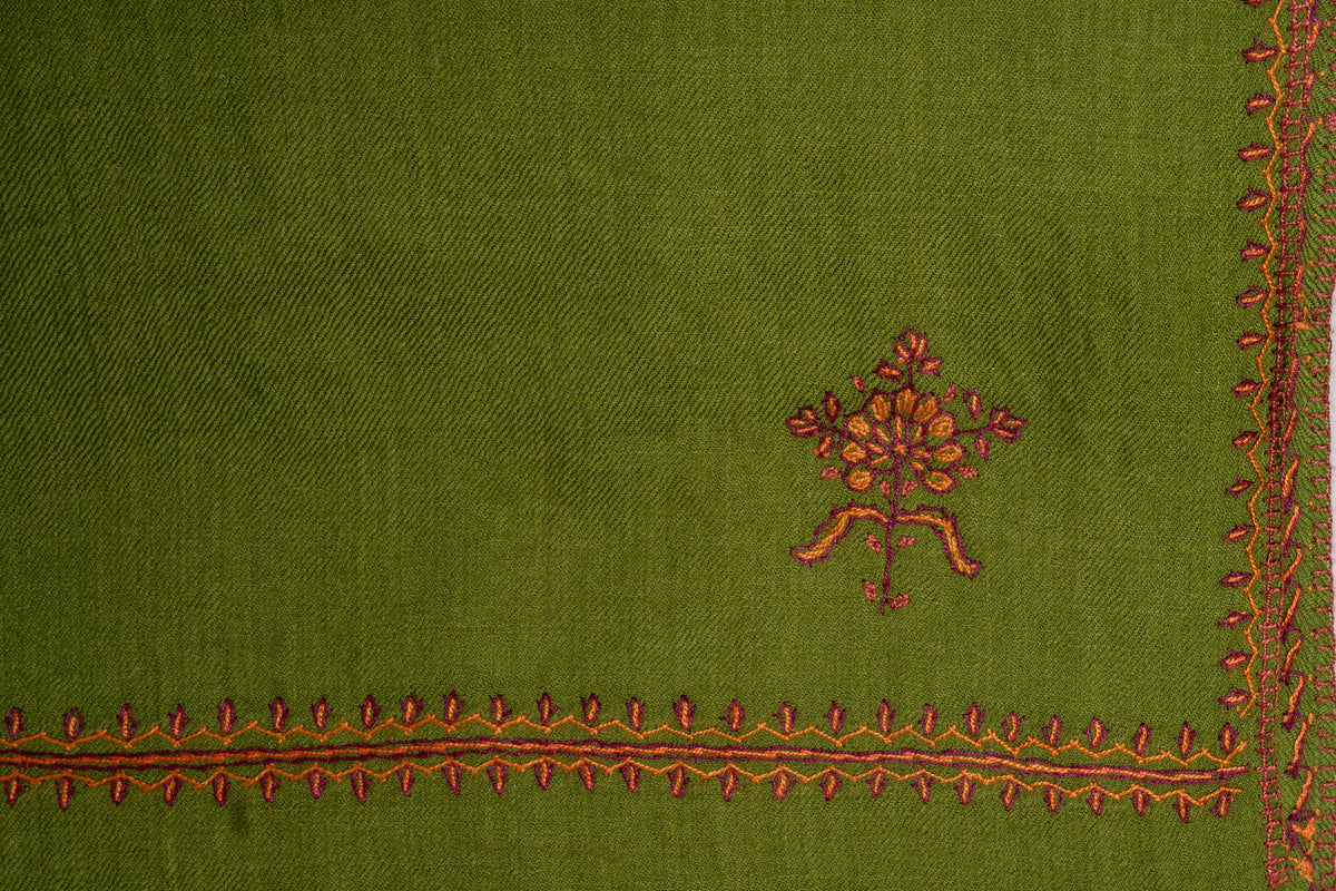 Close-up of a red and orange Sozni floral motif inside a narrow leaf border on a green Merino wool stole