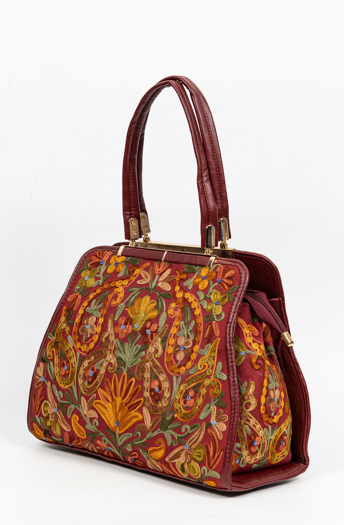 Opposite angled view of a maroon handbag with colourful Aari paisleys and flowers across the front and side panel
