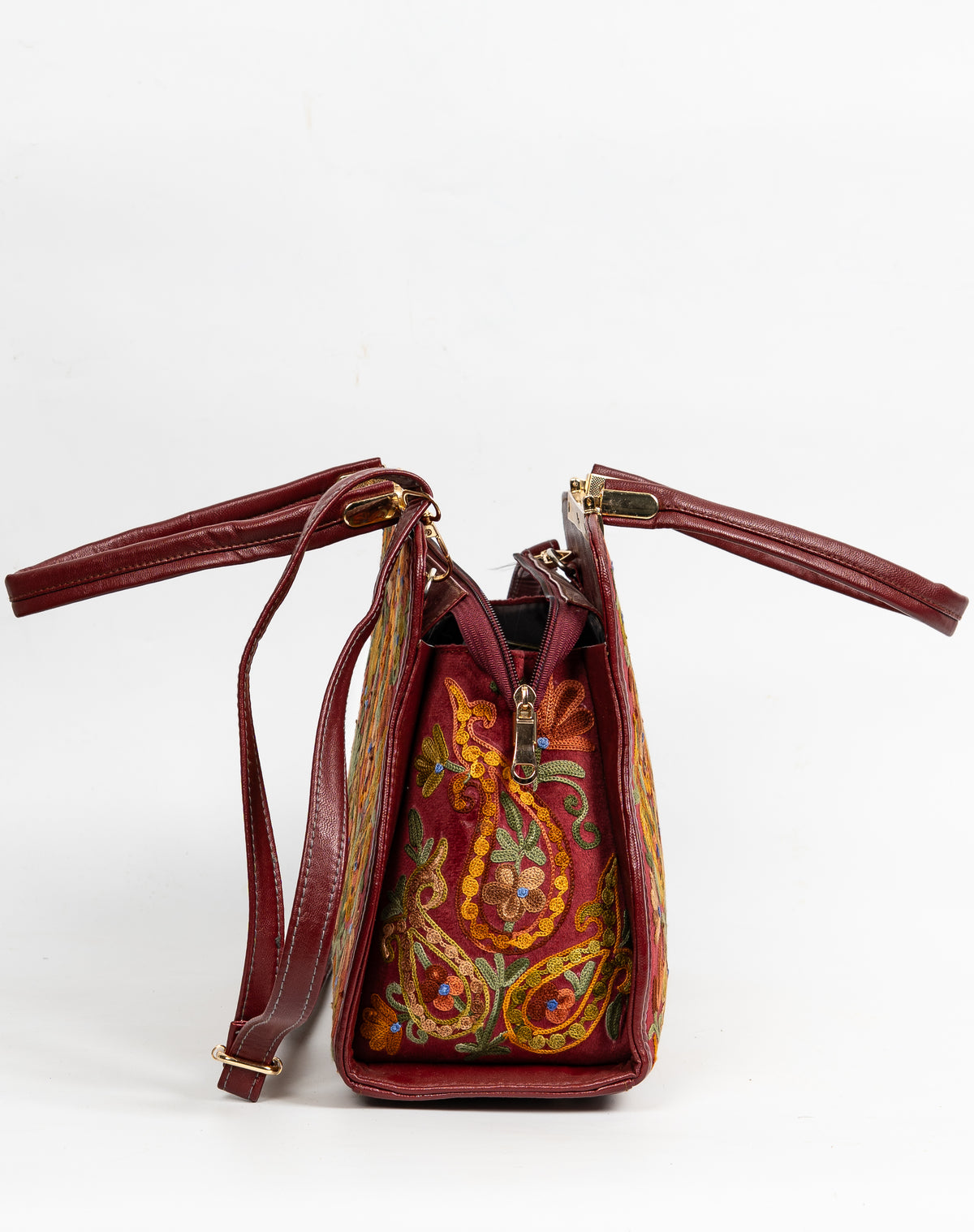 Side view of an open maroon handbag with a colourful Aari paisley panel, gold-toned fittings and attached shoulder strap