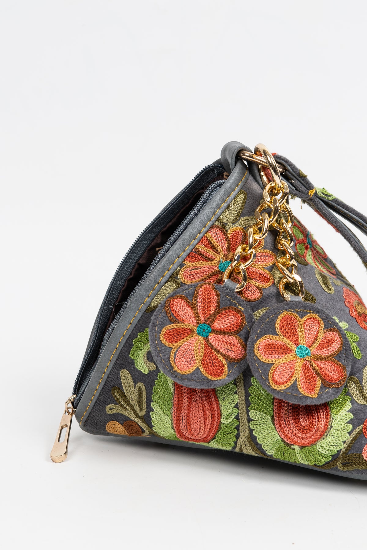 Close-up of the pyramid bag’s coral flower charms hanging from a gold-toned chain beside the zip opening