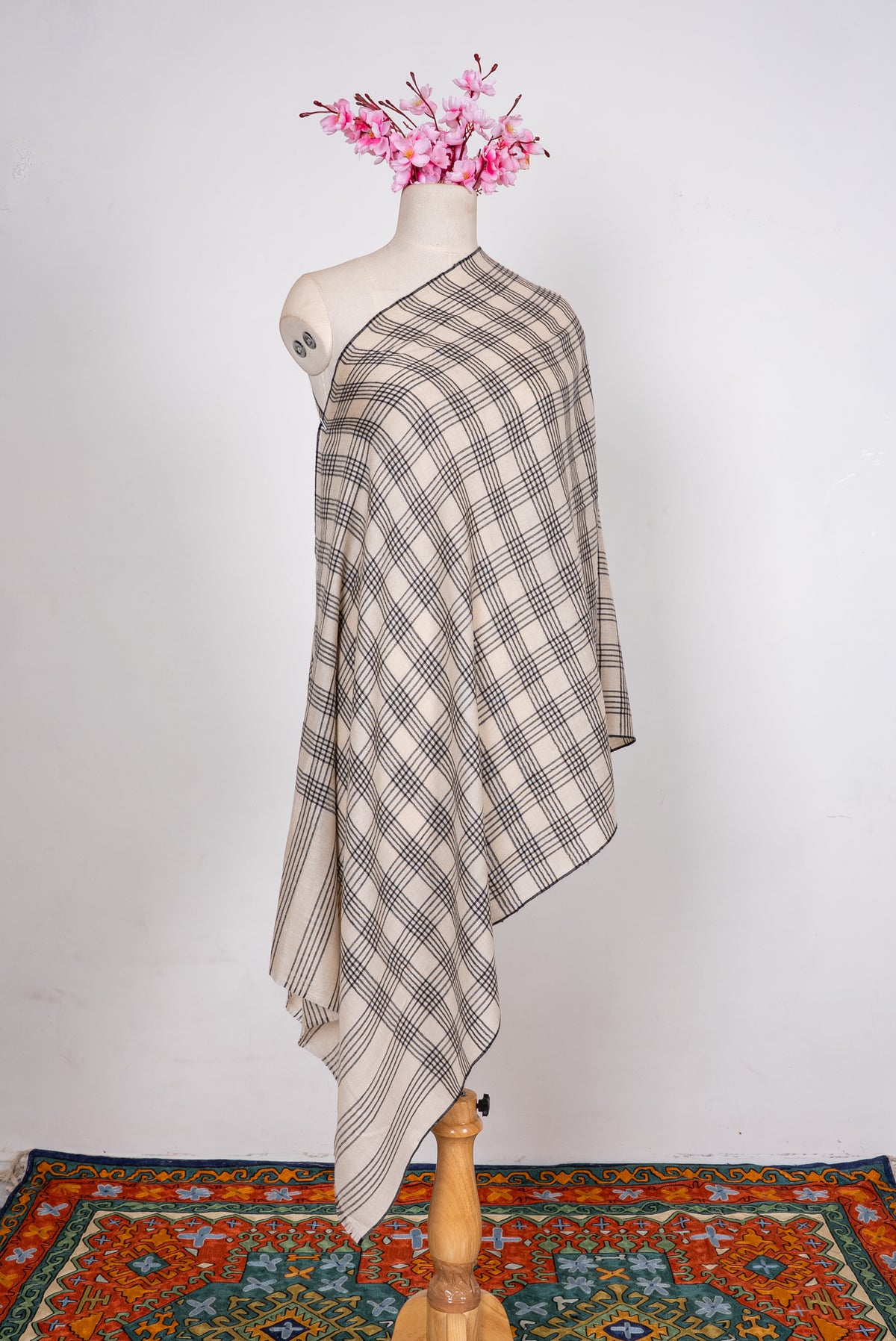 Full-length ivory Pashmina scarf draped over one shoulder, with black plaid checks and a striped end