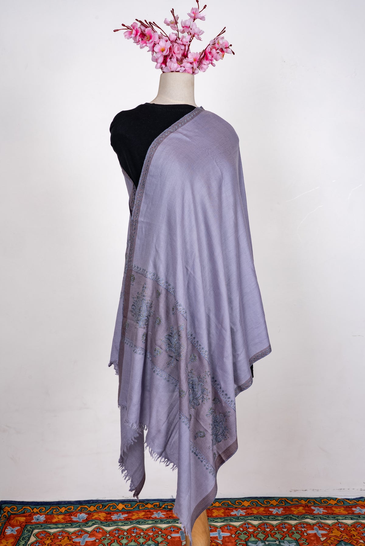 Lavender scarf draped on a mannequin, with fine embroidered side borders and a mauve floral end band above short fringe.