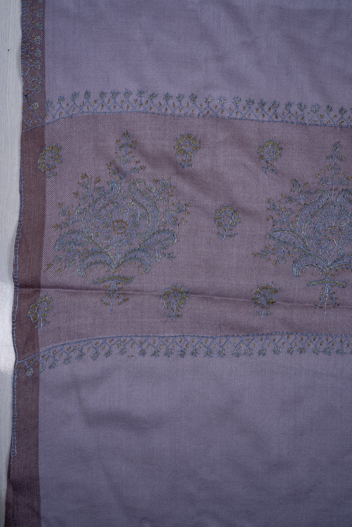 Flat close-up of the lavender scarf's mauve end band, with blue-and-olive embroidered floral bouquets, small sprigs and fine borders.