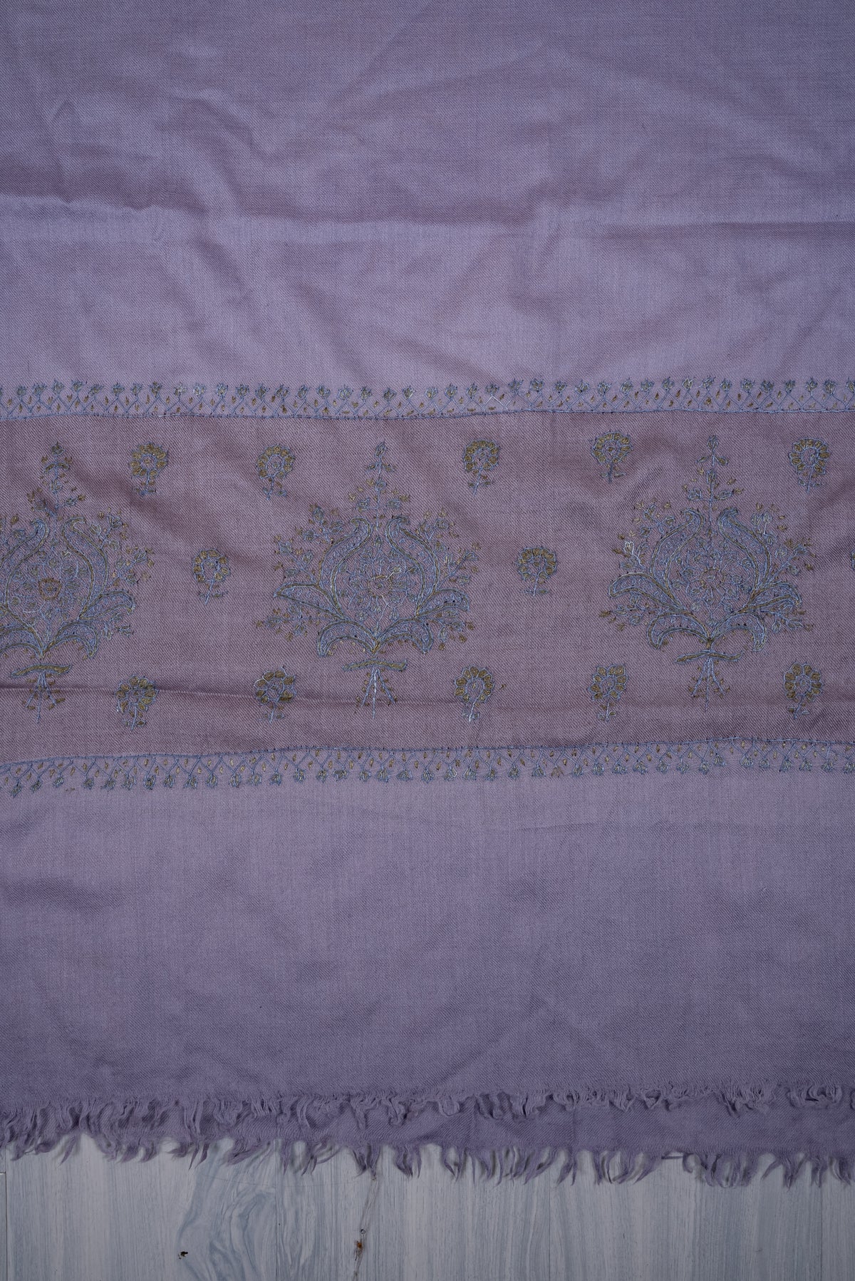 Lavender scarf end laid flat, with a mauve band of blue-and-olive floral embroidery above a plain section and short fringe.