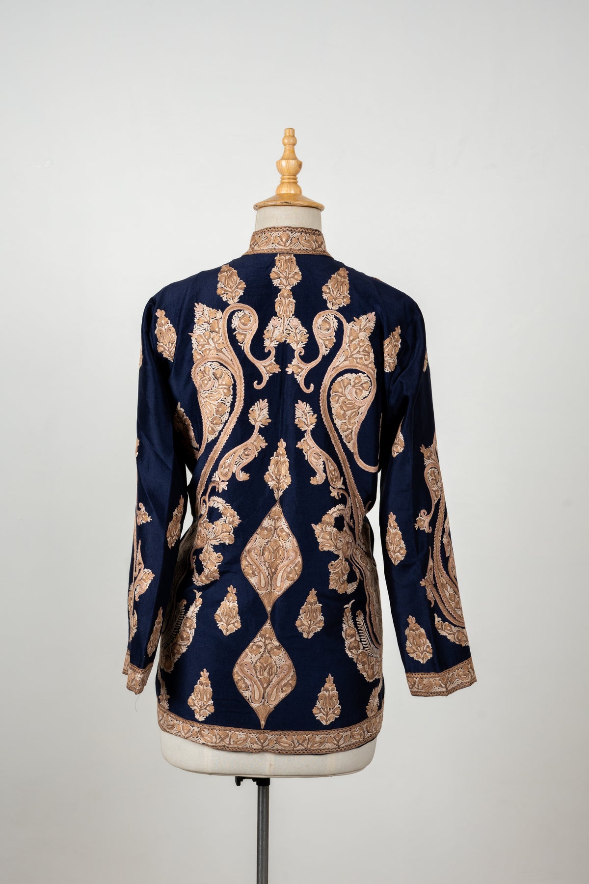 Back of a navy jacket with large beige Aari paisleys, smaller leaf motifs and embroidered collar, cuff and hem borders