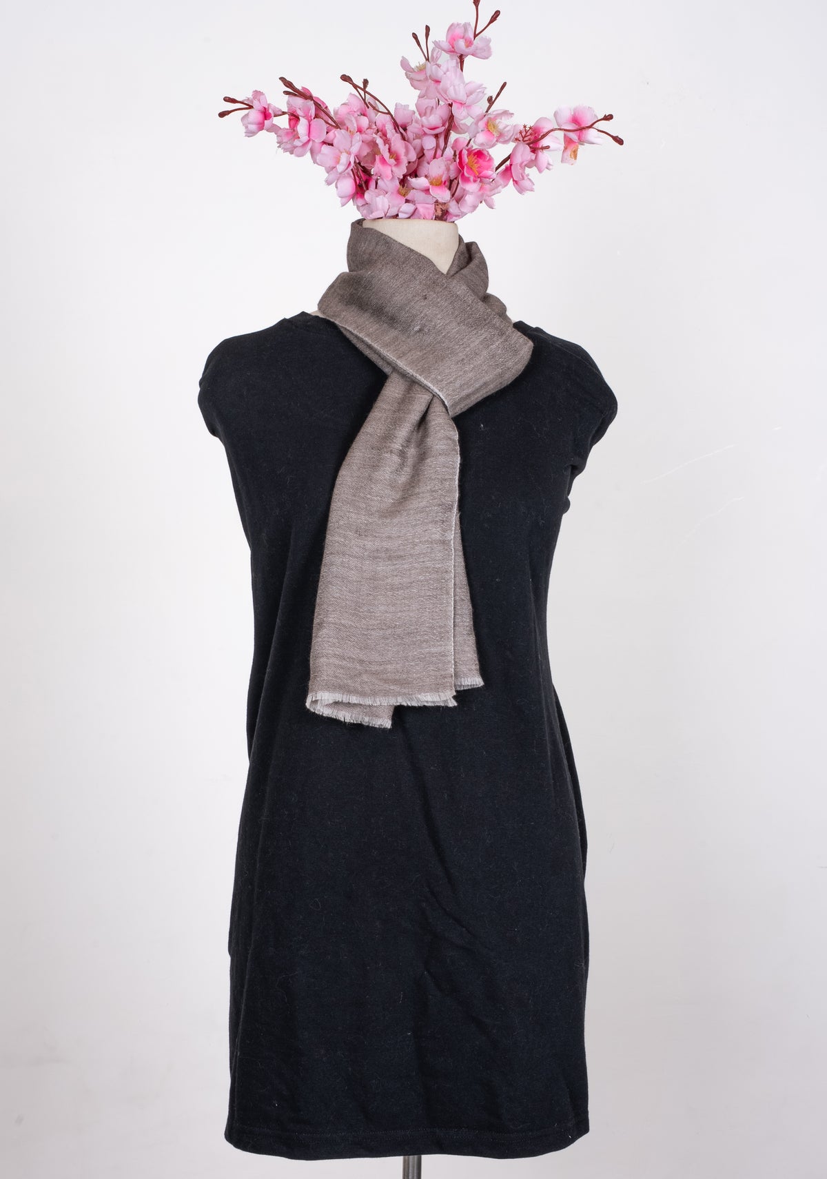 Taupe reversible wool muffler looped around a mannequin neck, with pale-edged ends hanging at the chest