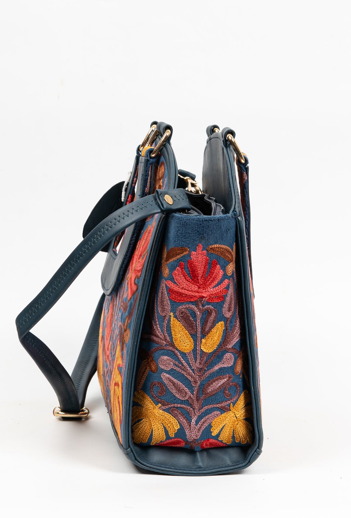 Side view of a navy handbag with red and yellow Aari flowers, an attached shoulder strap and gold-toned fittings