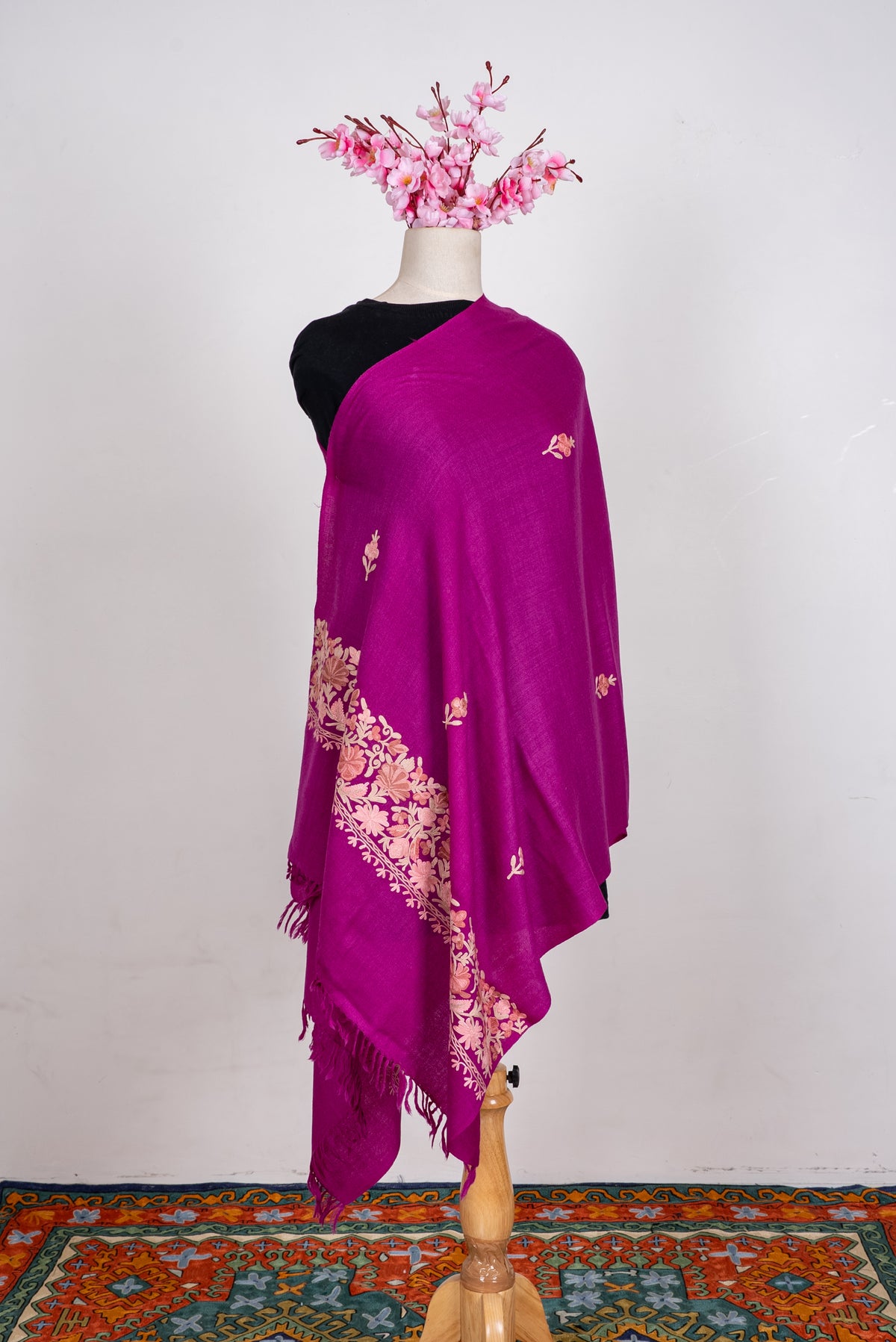 Full view of the magenta scarf on a mannequin, with scattered pale floral sprigs and a broad embroidered end border