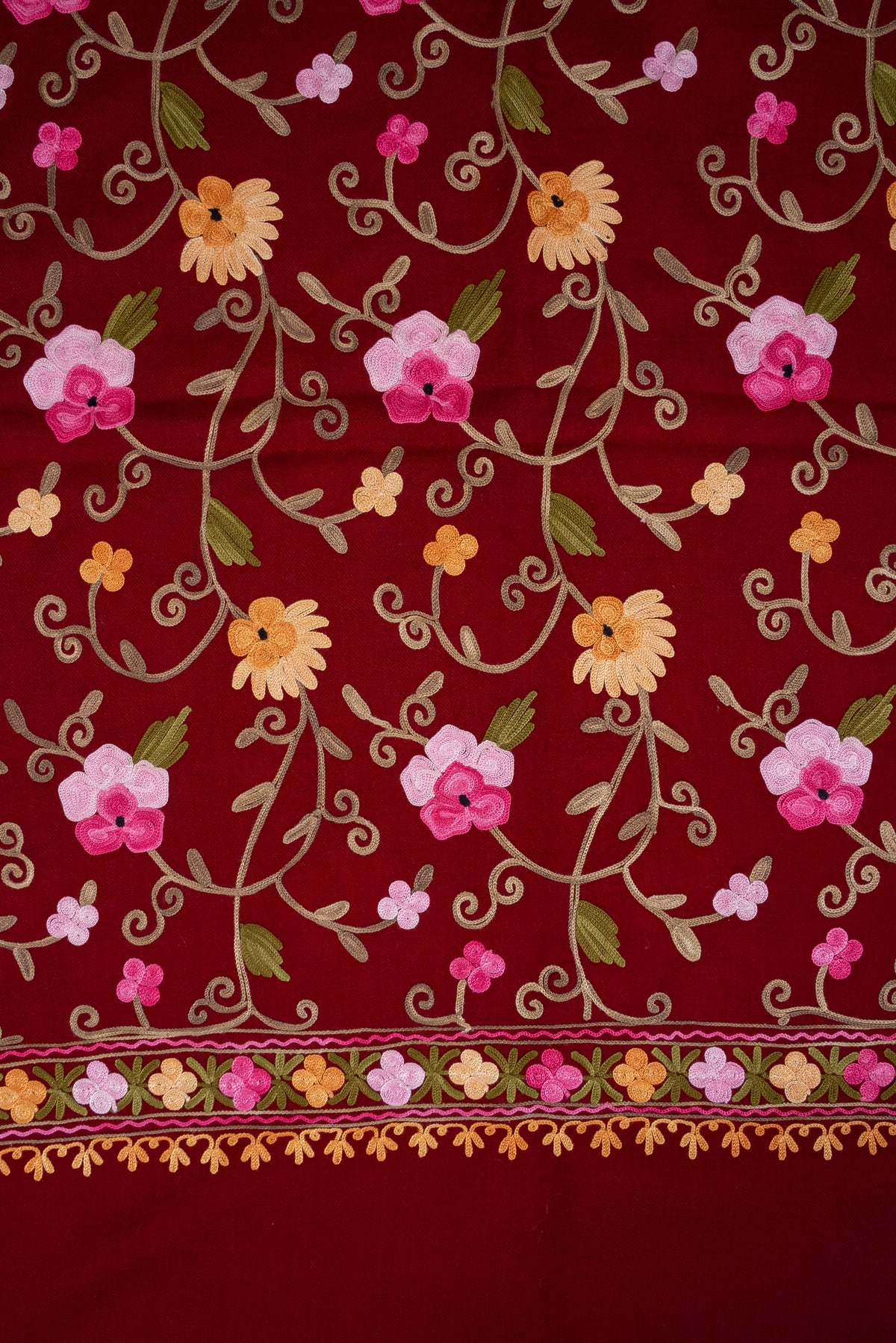 Maroon shawl detail with rows of pink and golden floral vines above the embroidered end border