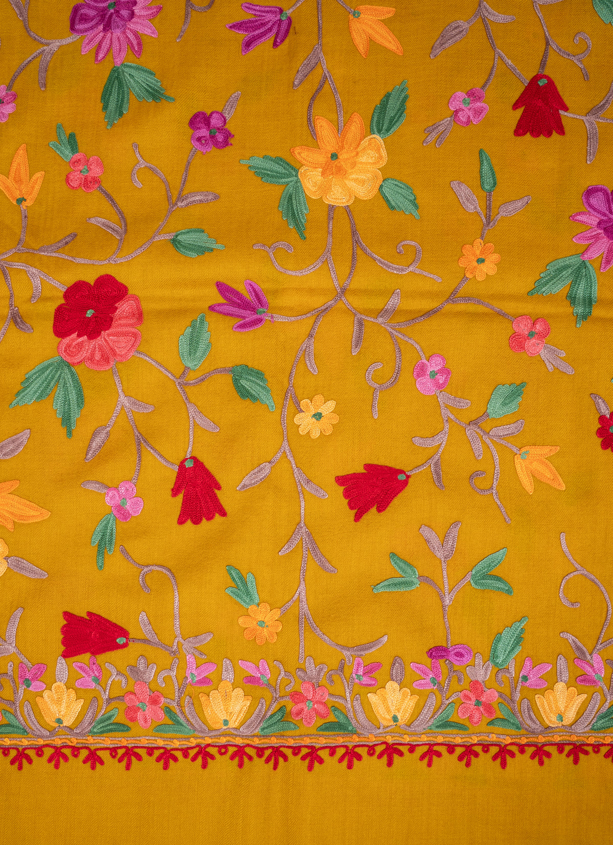 Mustard shawl detail showing colourful floral vines above a narrow embroidered end border