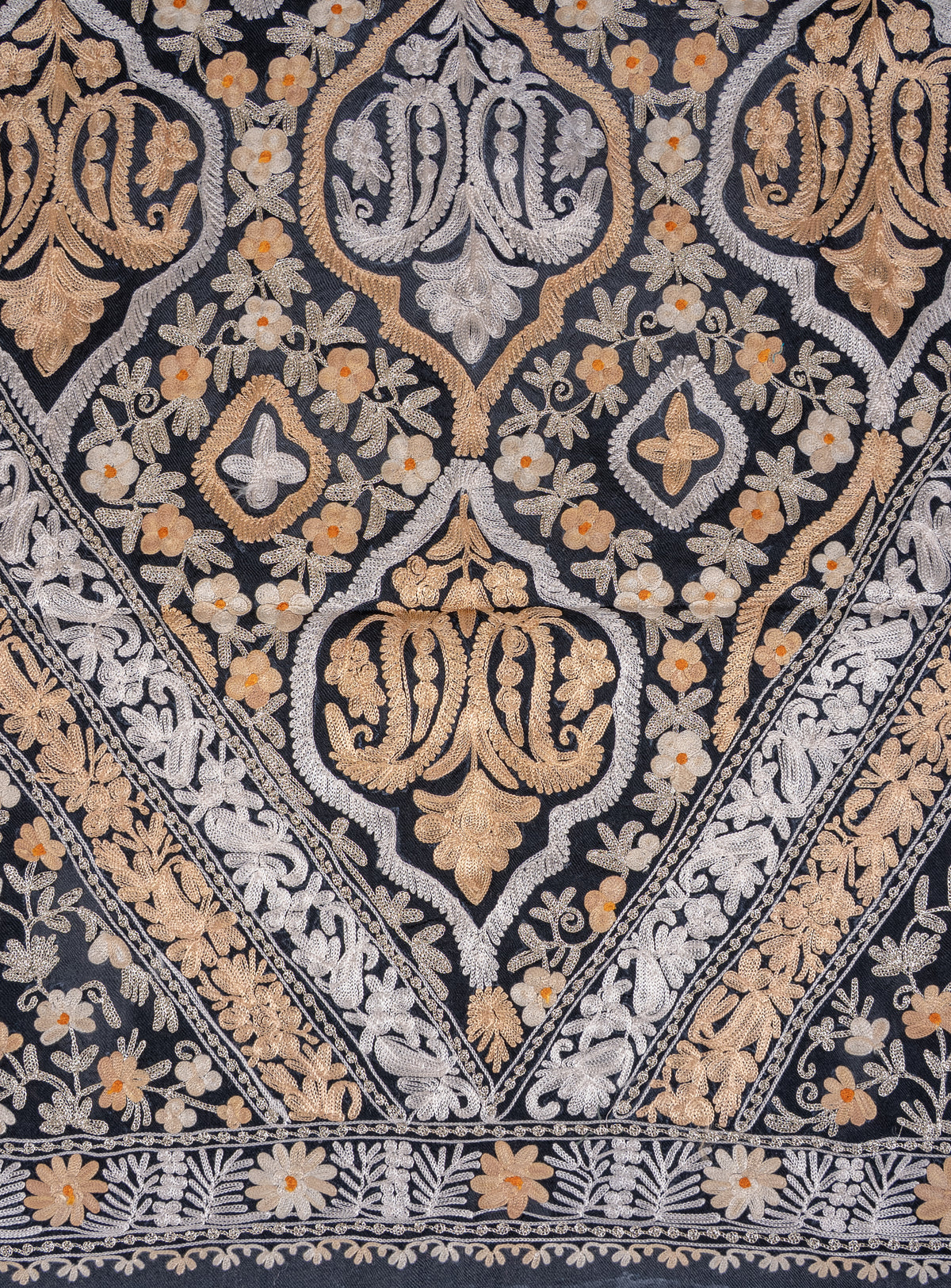 Close-up of the black shawl’s ivory and gold-toned Aari medallions framed by small flowers and diagonal leafy bands