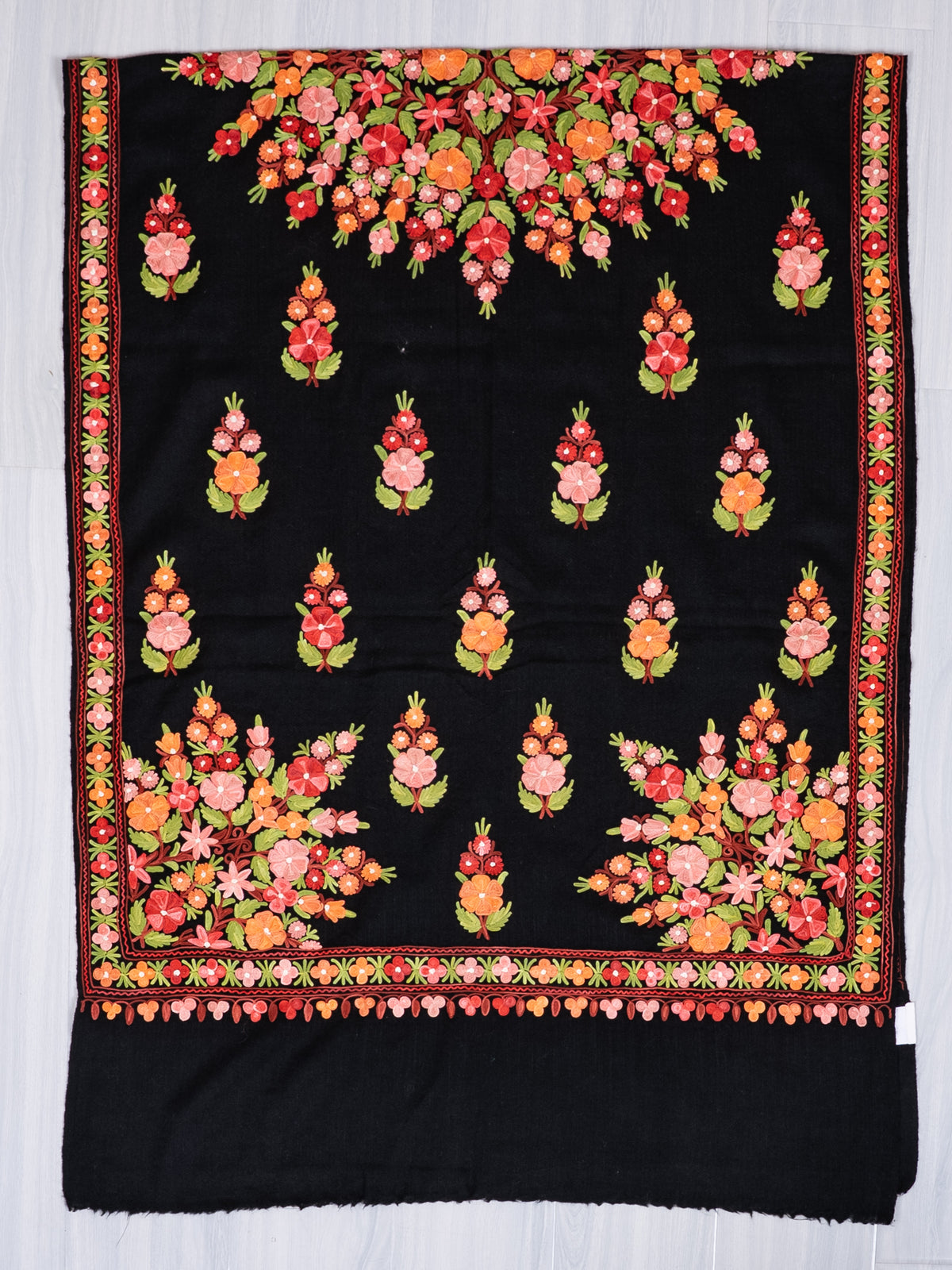 Black shawl spread flat, with multicoloured bouquets, large floral corner panels, patterned borders and a plain black end